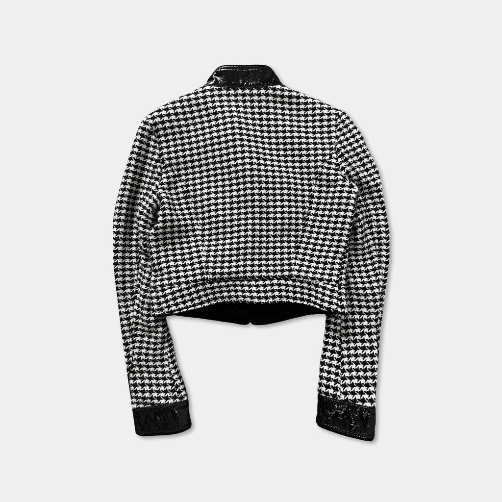A black and white checkered jacket with a collar and long sleeves, displayed against a plain background.