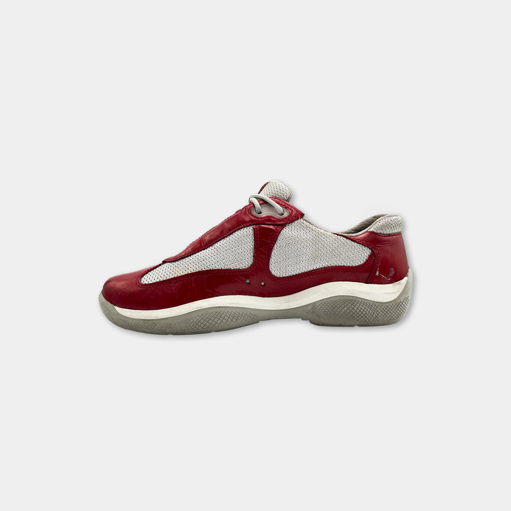 A red and white sneaker with a white sole and mesh panel on the side.