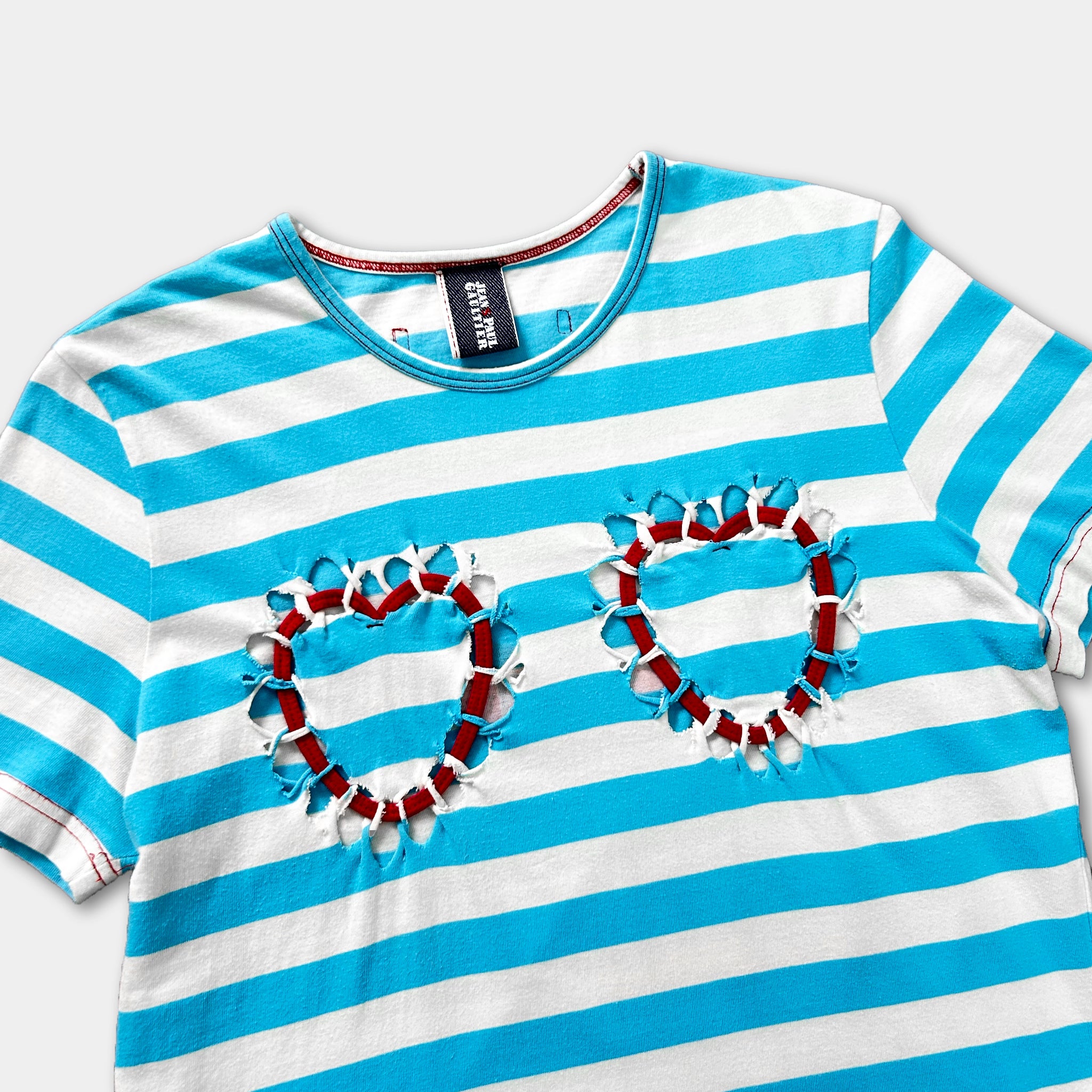 A striped t-shirt with two heart-shaped cutouts on the front, made of red and white fabric.