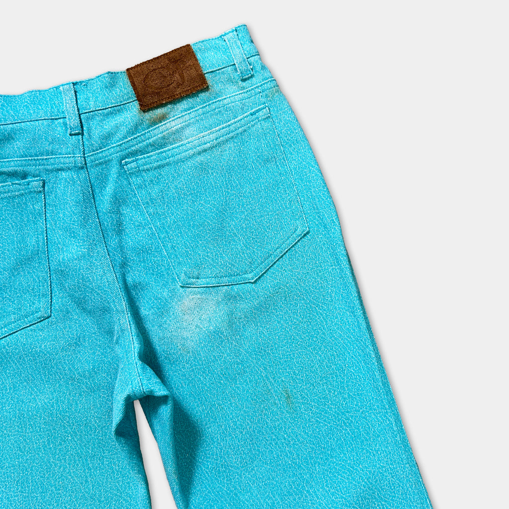A pair of bright blue denim jeans with a brown leather patch on the back pocket.