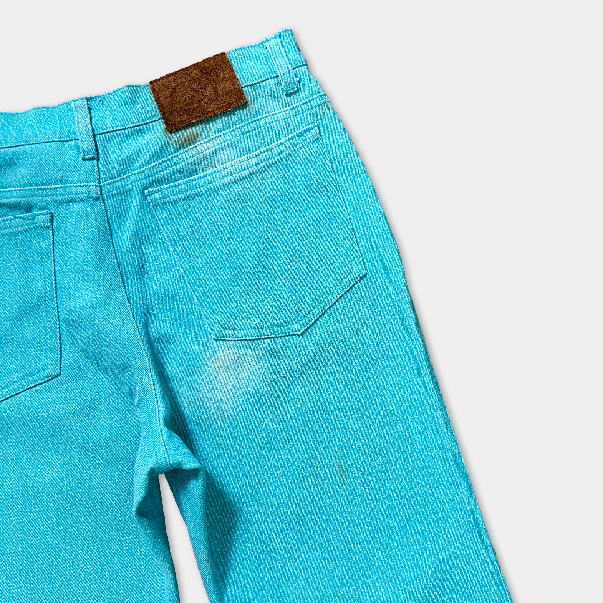 A pair of bright blue denim jeans with a brown leather patch on the back pocket.