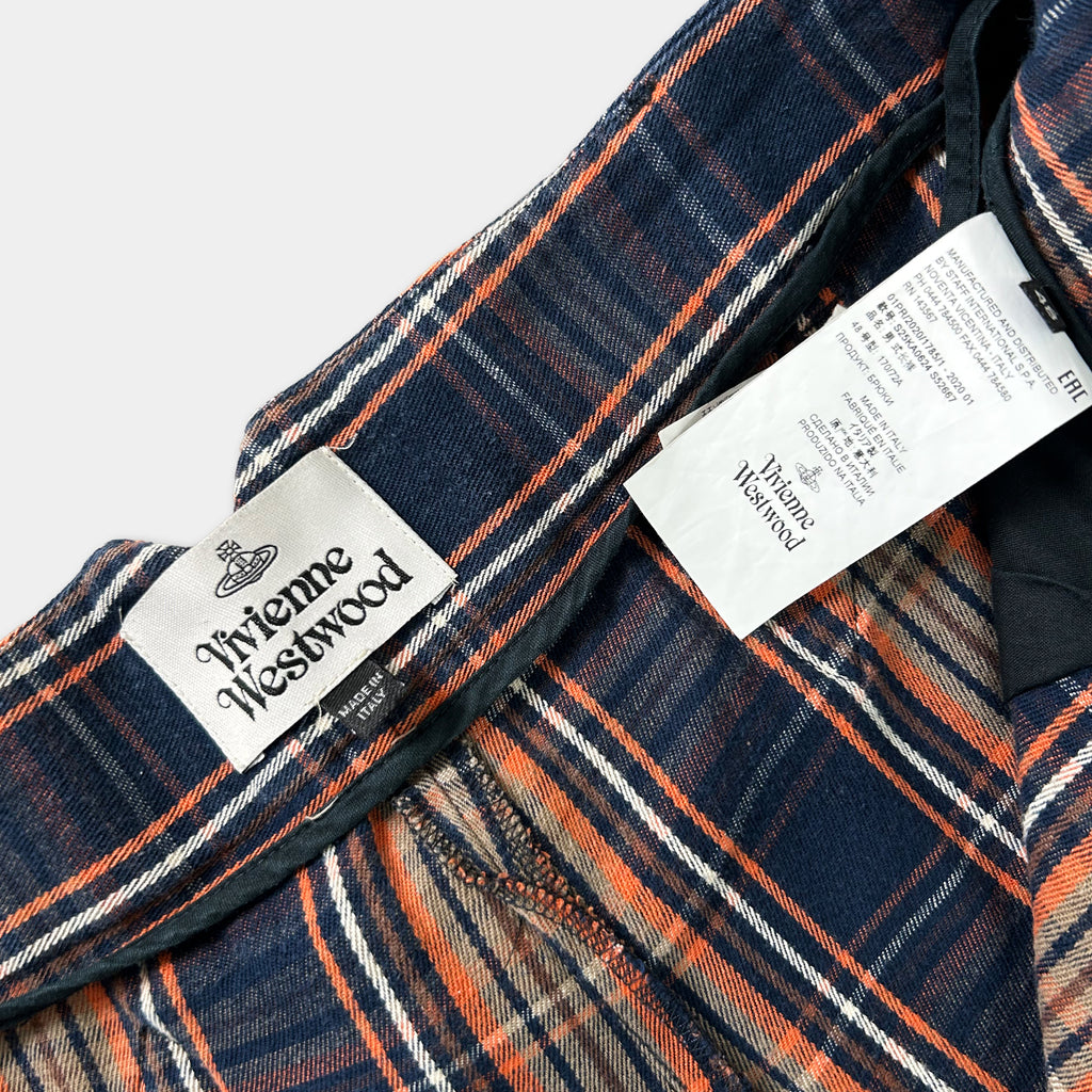 a close-up view of a plaid fabric, possibly a jacket or a shirt, with a label attached to it. The label appears to be from the brand Vivienne Westwood, as indicated by the text on the label.