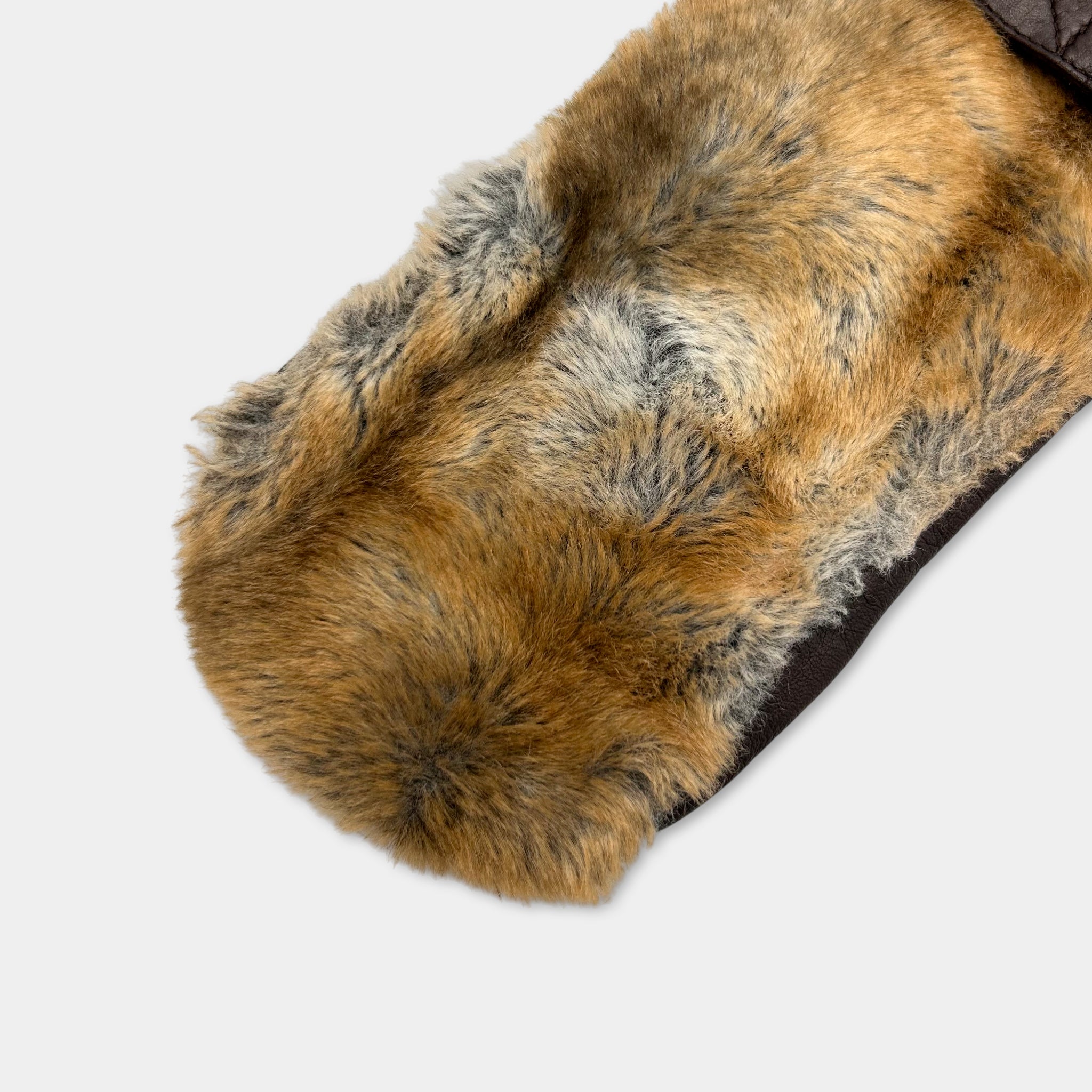 A close-up view of a furry fabric, possibly a piece of clothing or accessory, with a brown and gray color pattern.