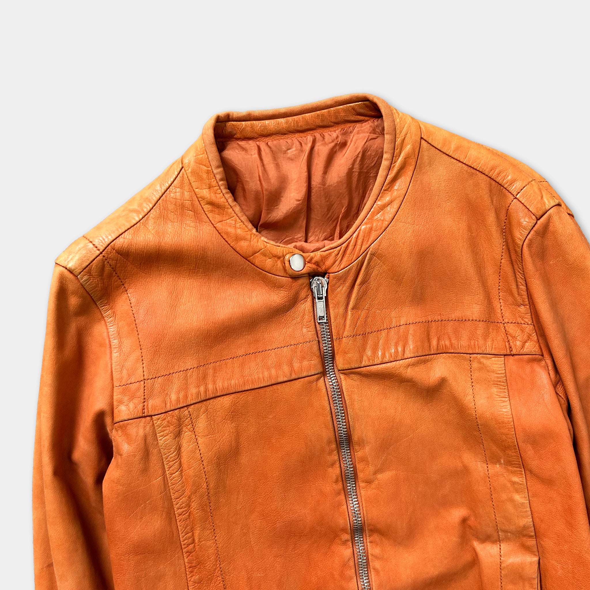 A close-up view of an orange leather jacket with a zipper and collar.