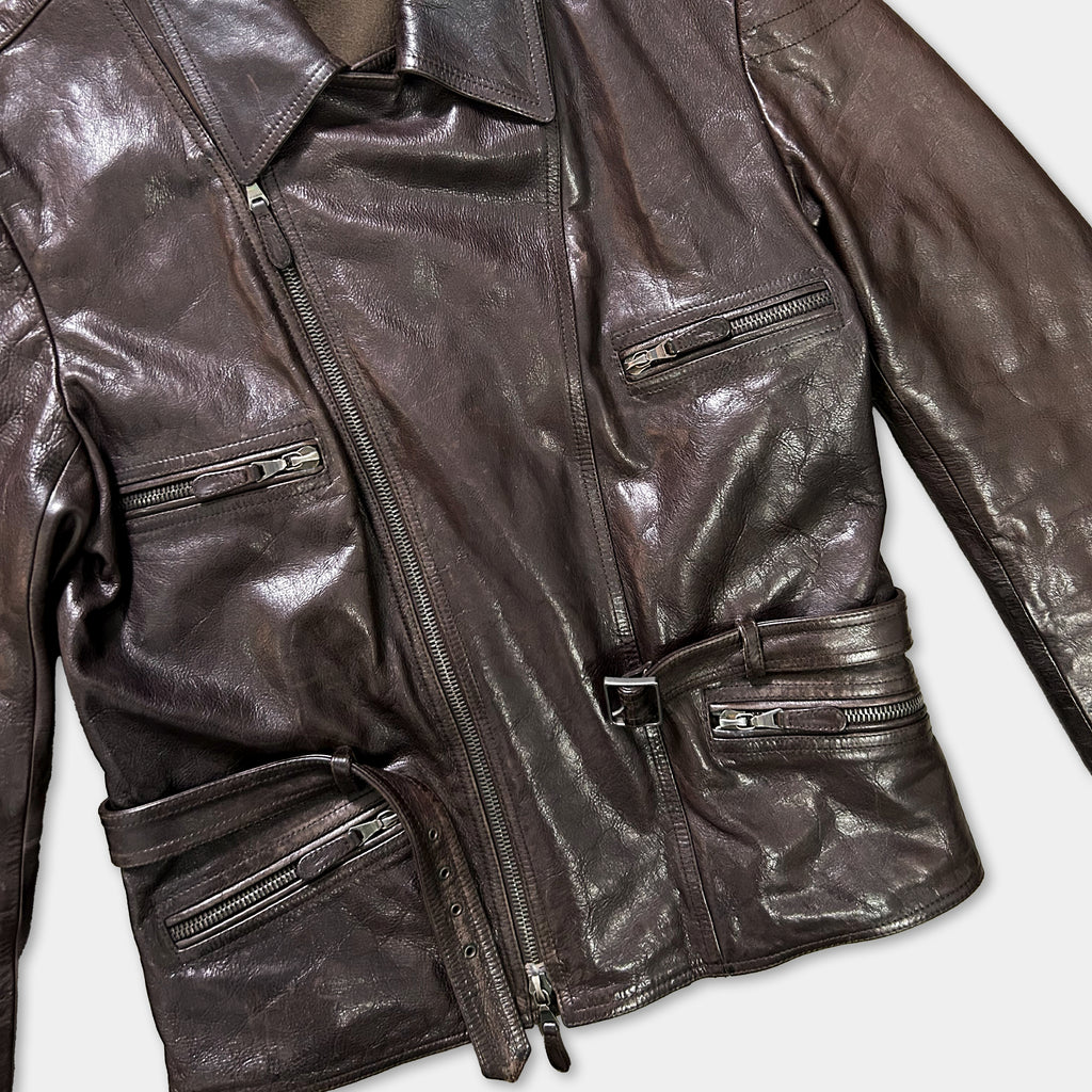 A close-up view of a brown leather jacket with multiple zippers and pockets.