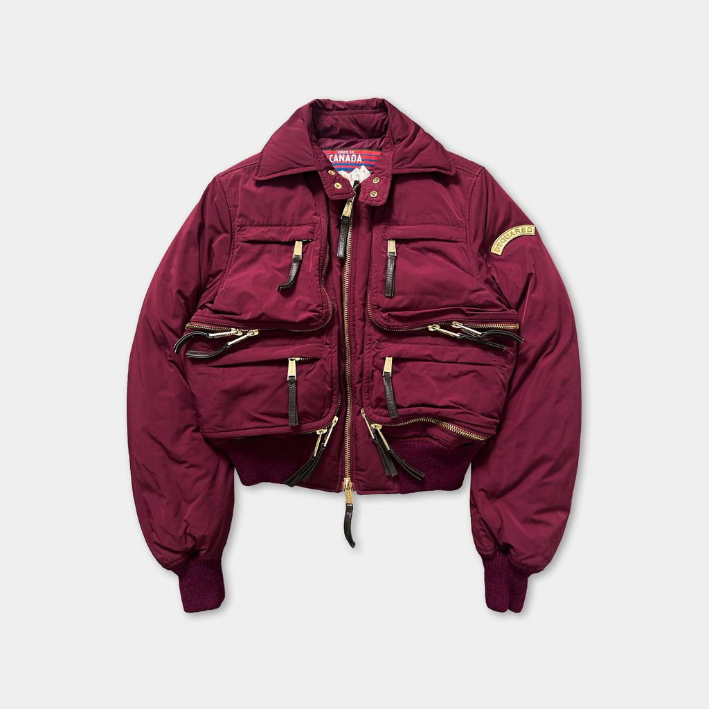 A burgundy-colored jacket with multiple pockets and zippers, featuring a collar and a zipper running down the front.