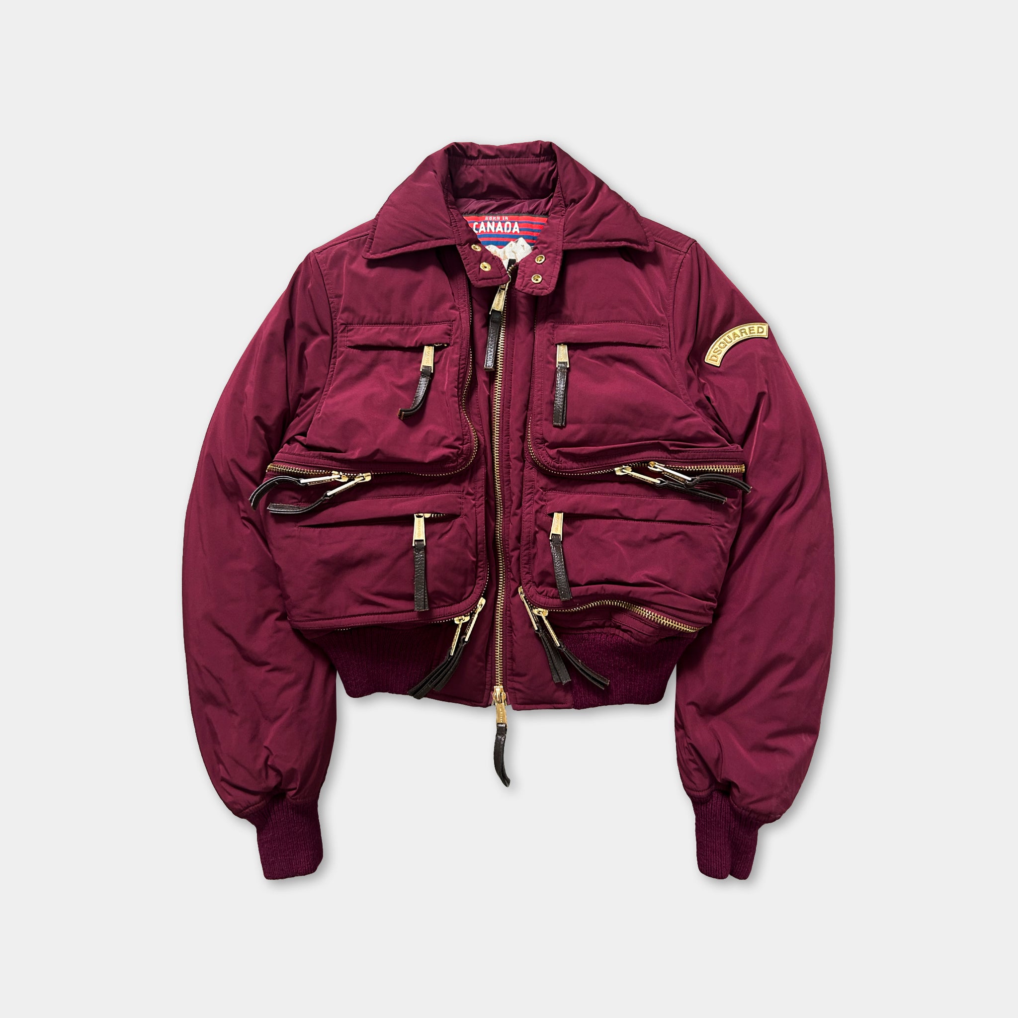 A burgundy-colored jacket with multiple pockets and zippers, featuring a collar and a zipper running down the front.
