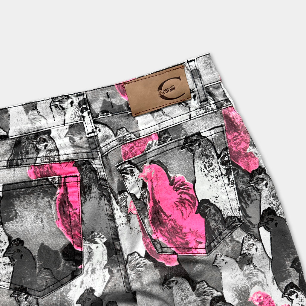 a pair of jeans with a unique printed pattern of pink and black birds on the fabric.