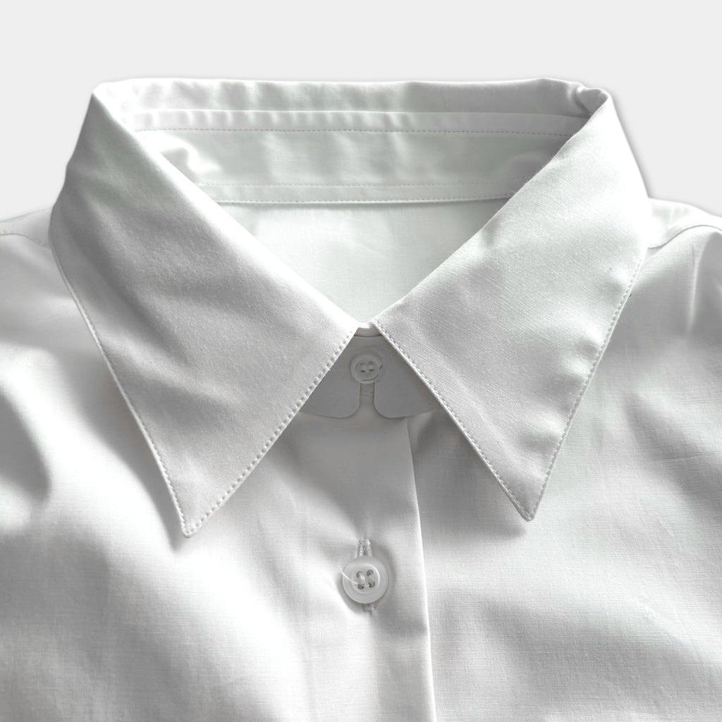 A close-up view of a white collared shirt, focusing on the collar and buttons.