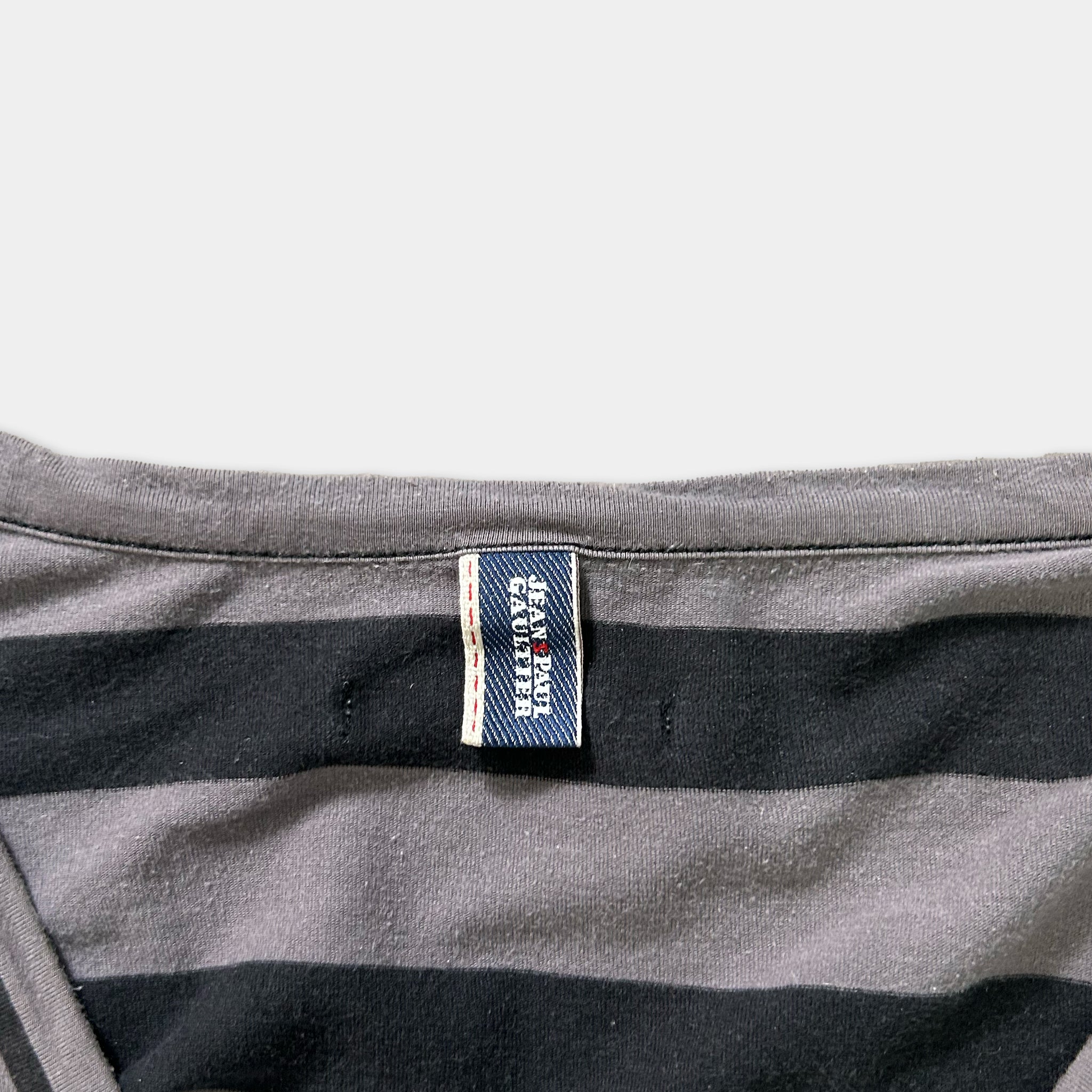 A gray and black striped shirt with a small blue label attached to the collar.