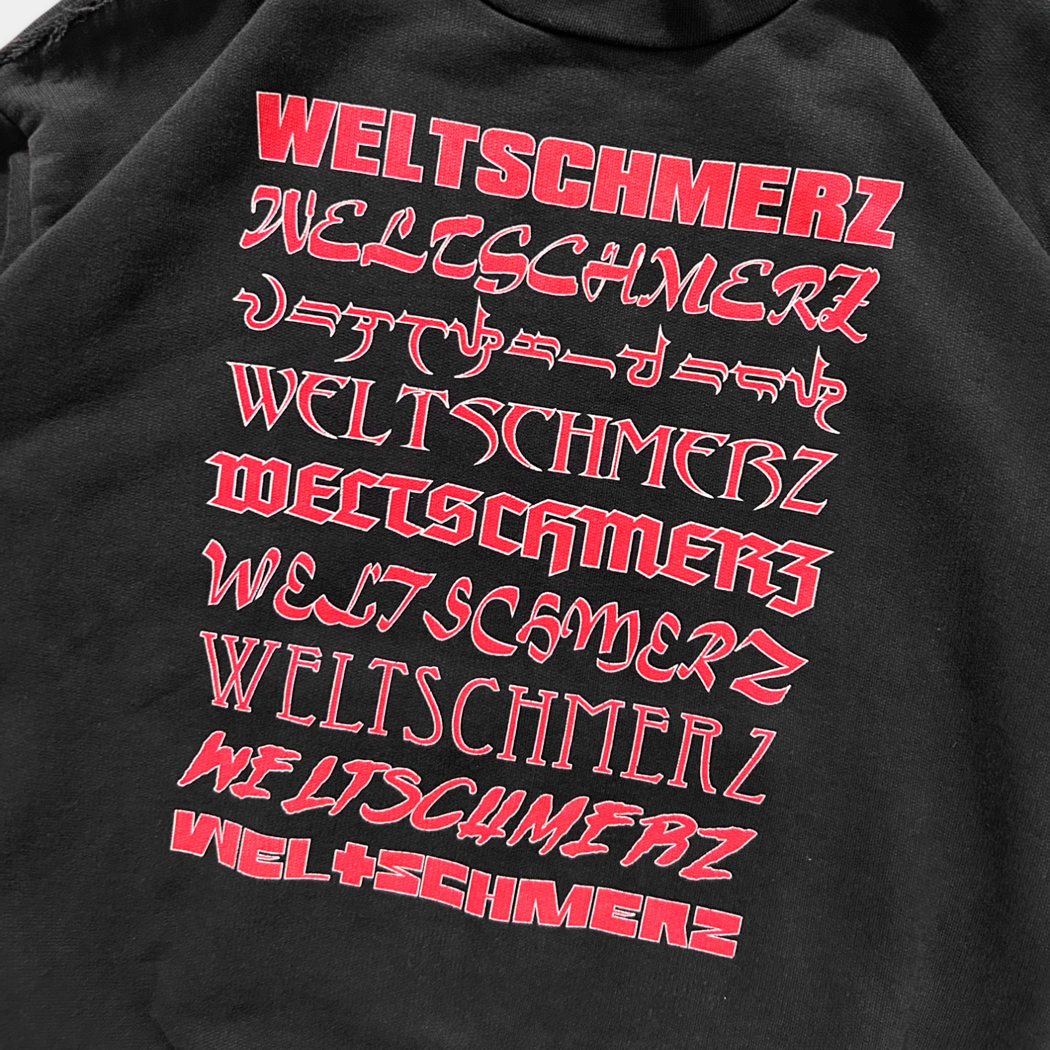 a black sweatshirt with red text that reads "WELTSCHMERZ" in a stylized font.