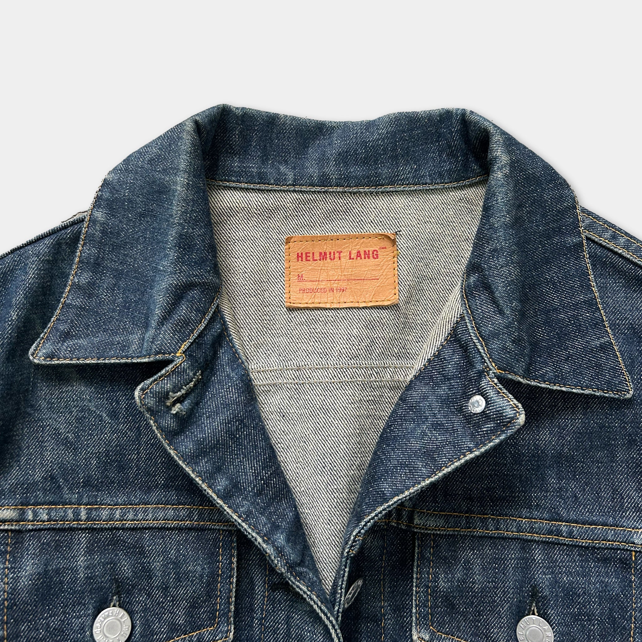 A close-up view of a denim jacket with a label on the collar.
