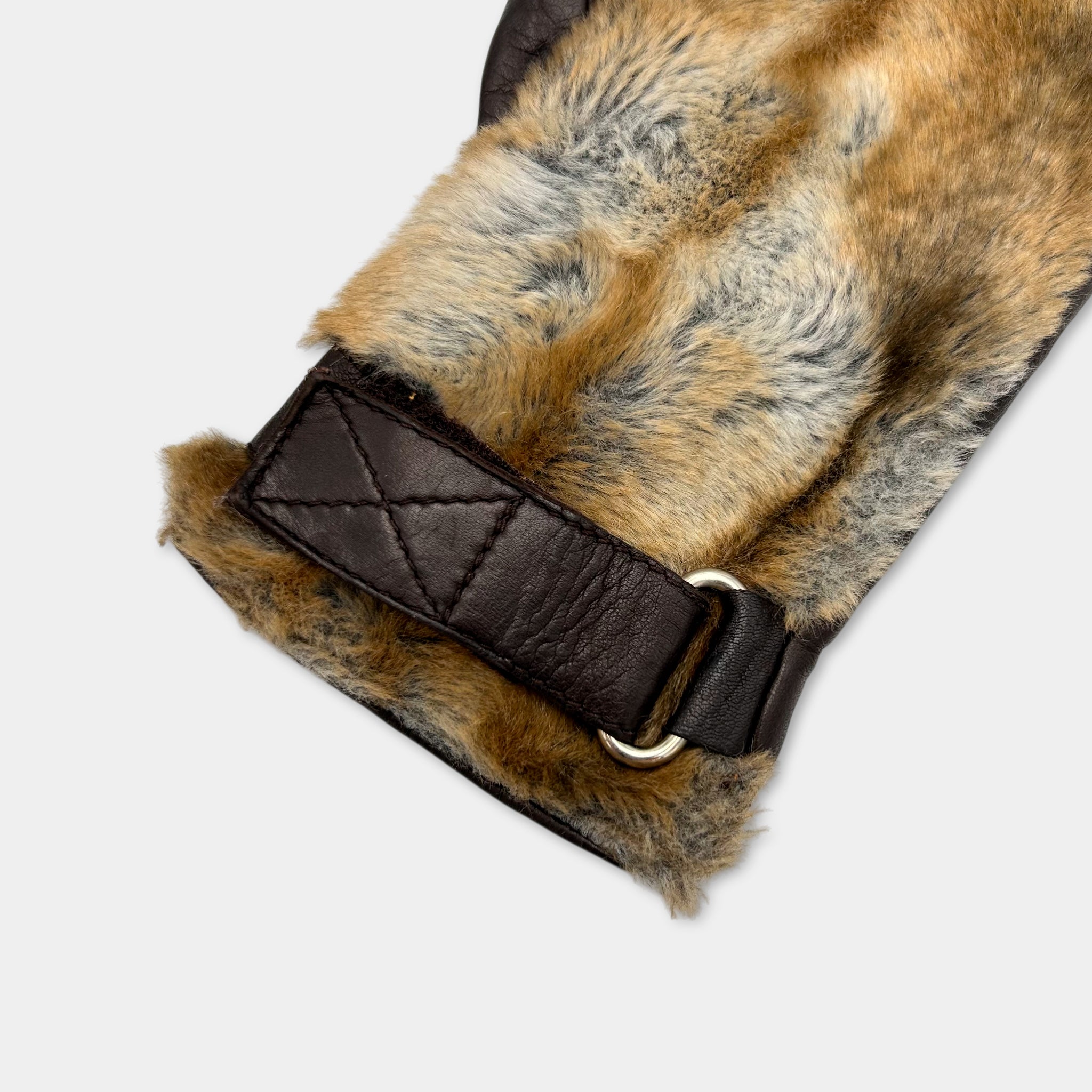 A close-up view of a leather glove with a fur-like texture, featuring a metal buckle and a black leather strap.