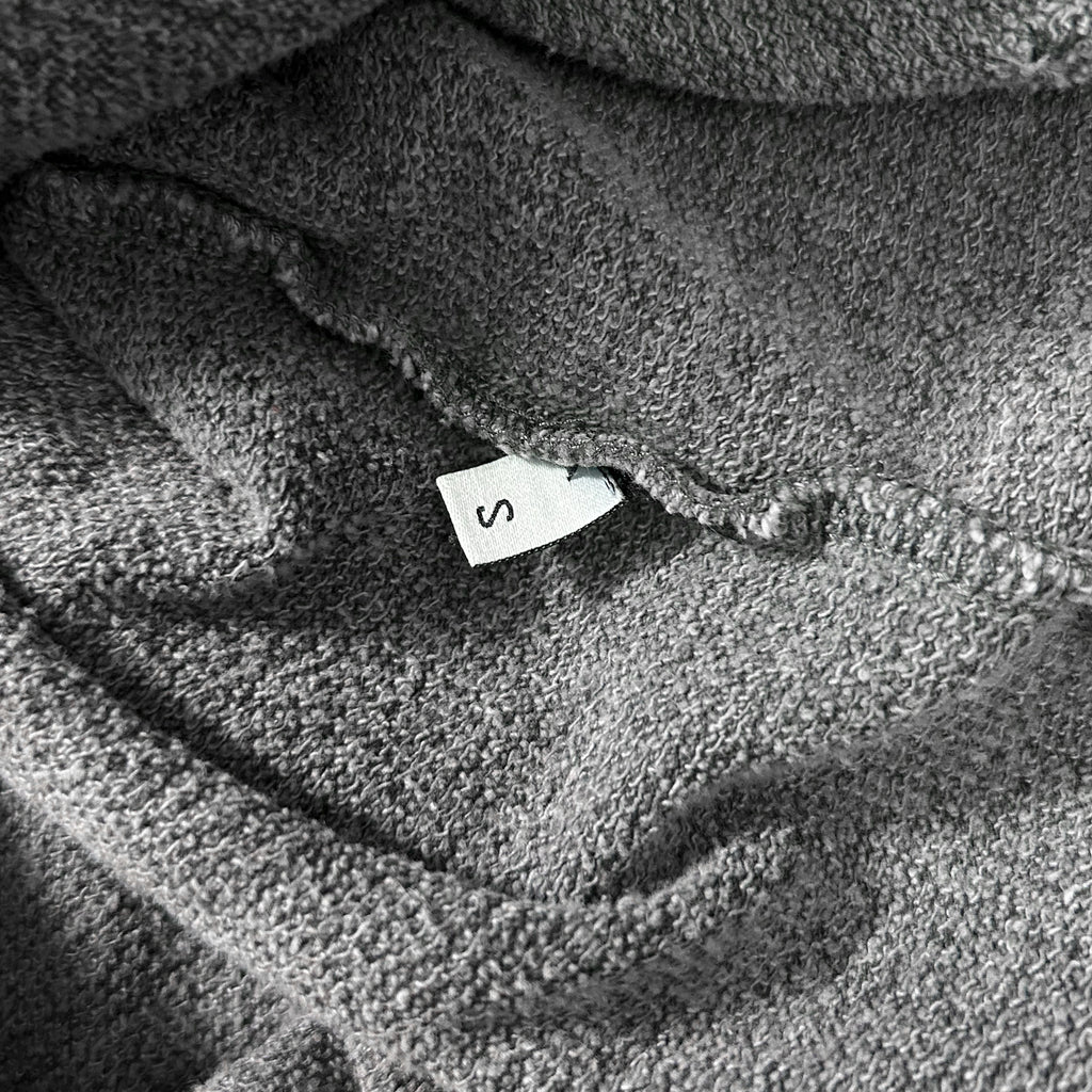 A close-up view of a grey, textured fabric with a small white label attached to it.