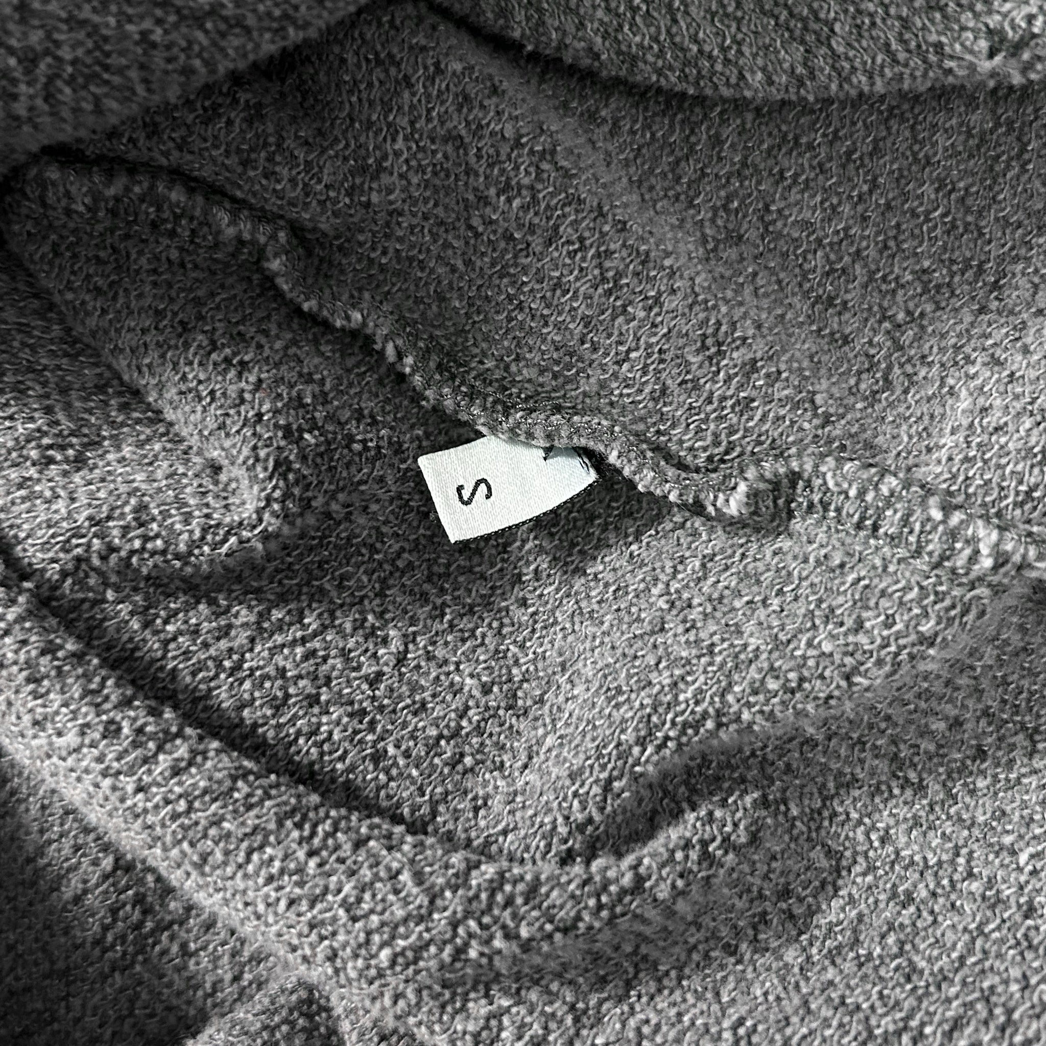 A close-up view of a grey, textured fabric with a small white label attached to it.
