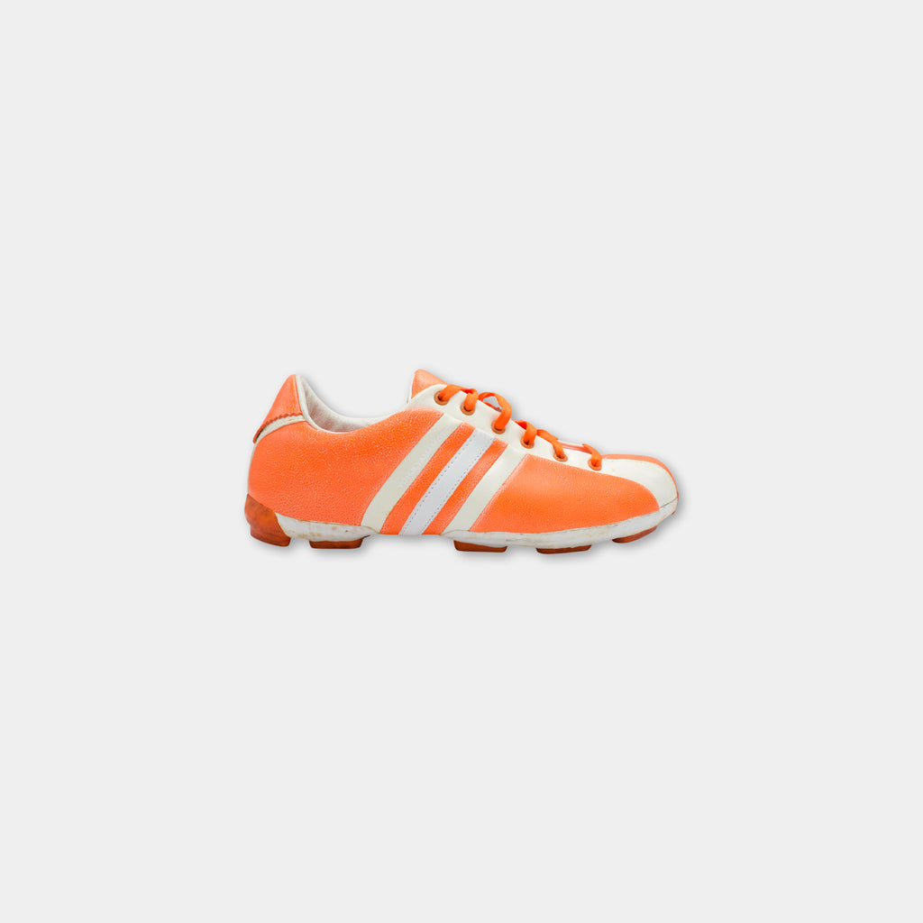 A single, bright orange and white Adidas cleat is shown against a plain white background.