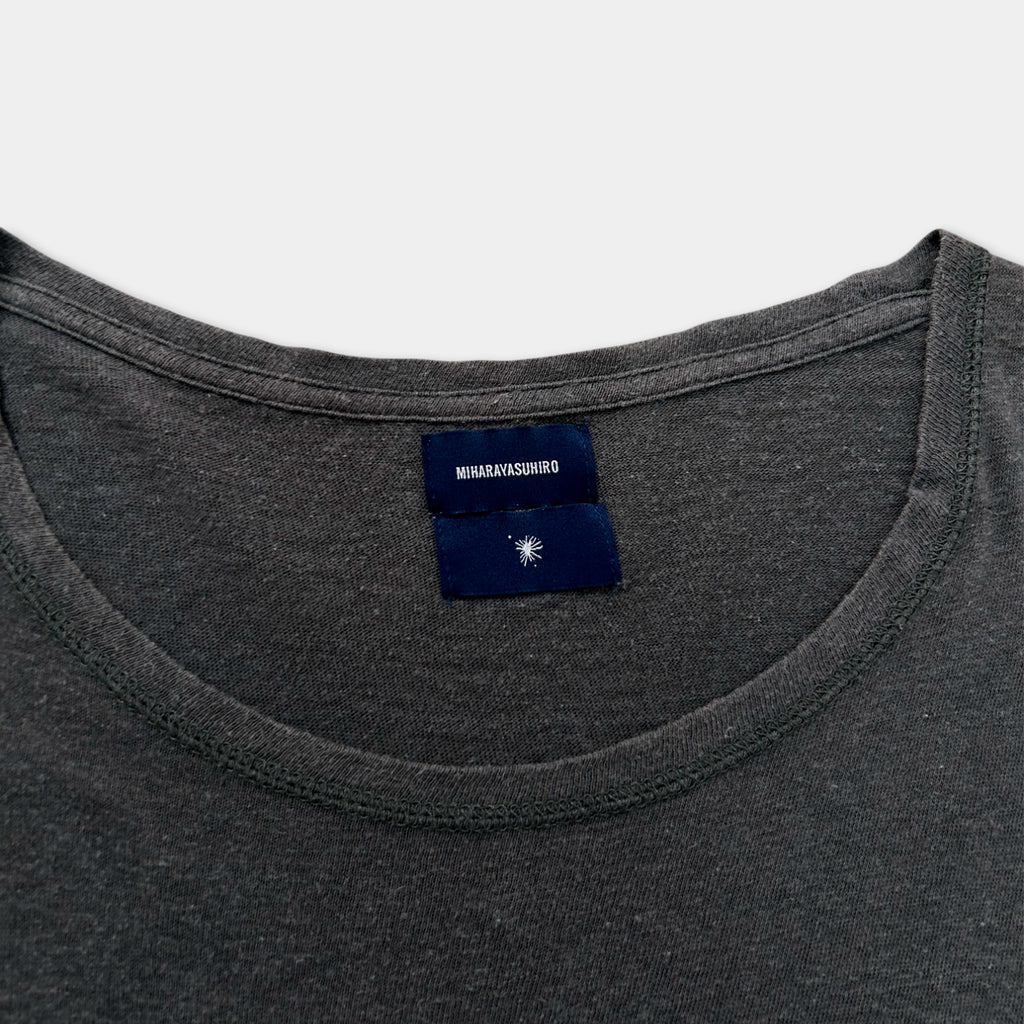 A gray t-shirt with a blue label on the collar.