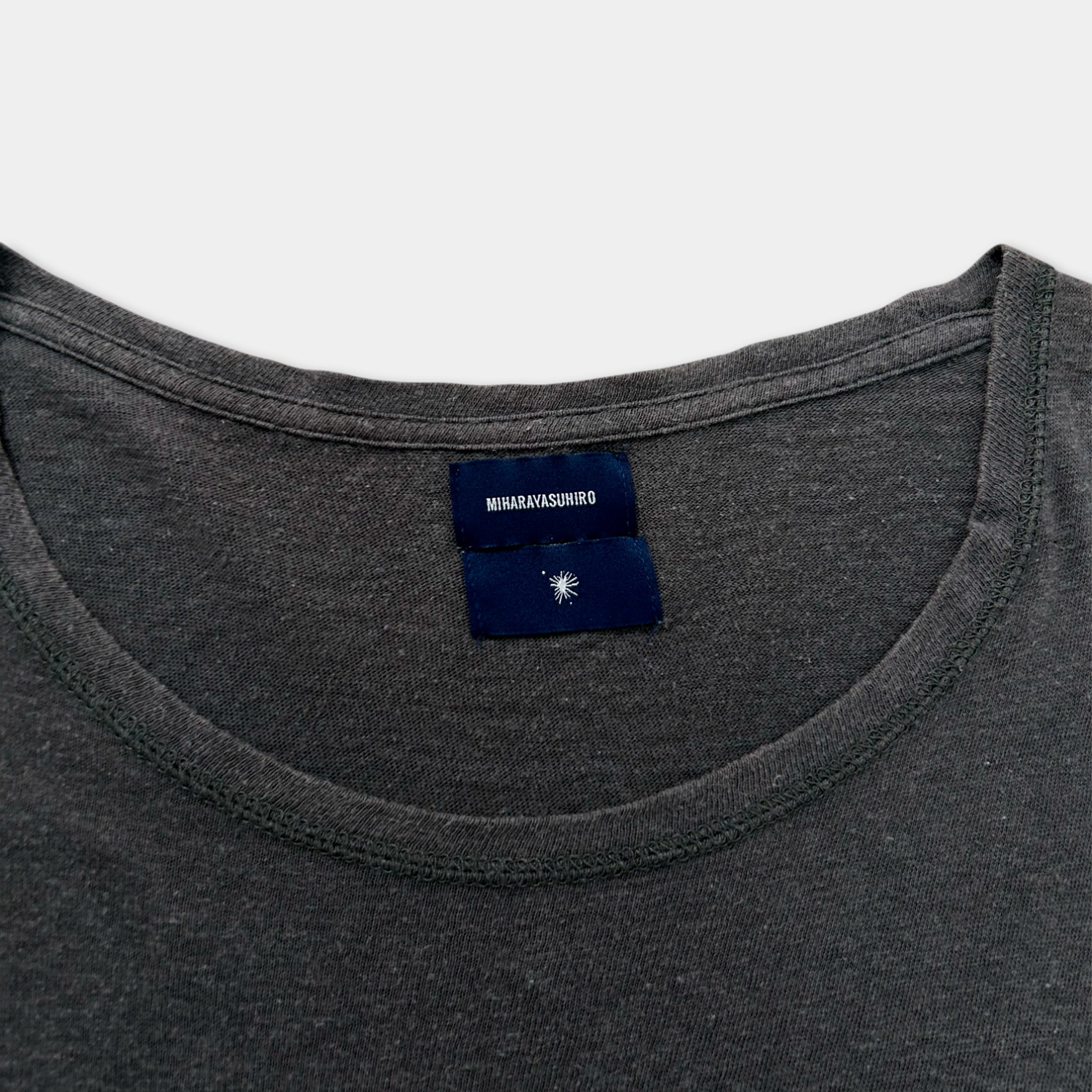 A gray t-shirt with a blue label on the collar.