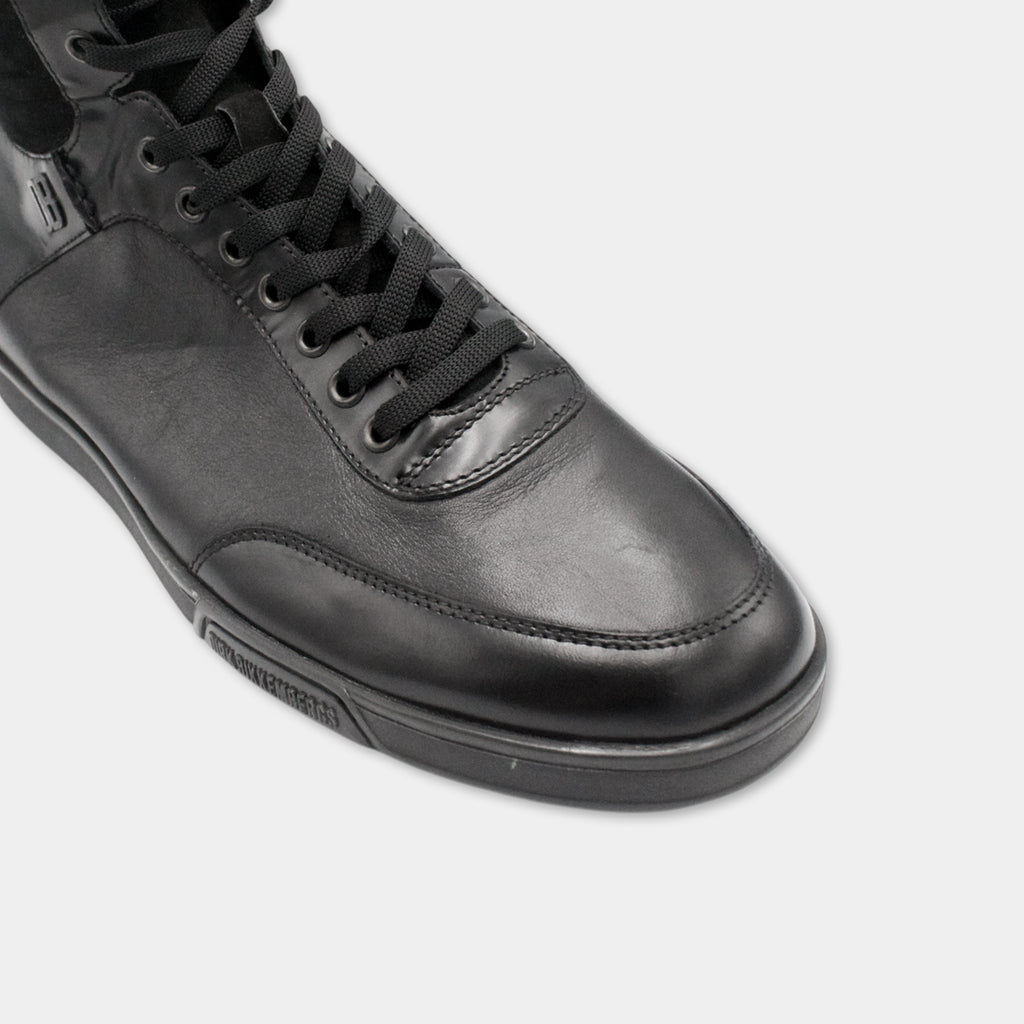 A close-up view of a black leather sneaker with a black lace and sole.