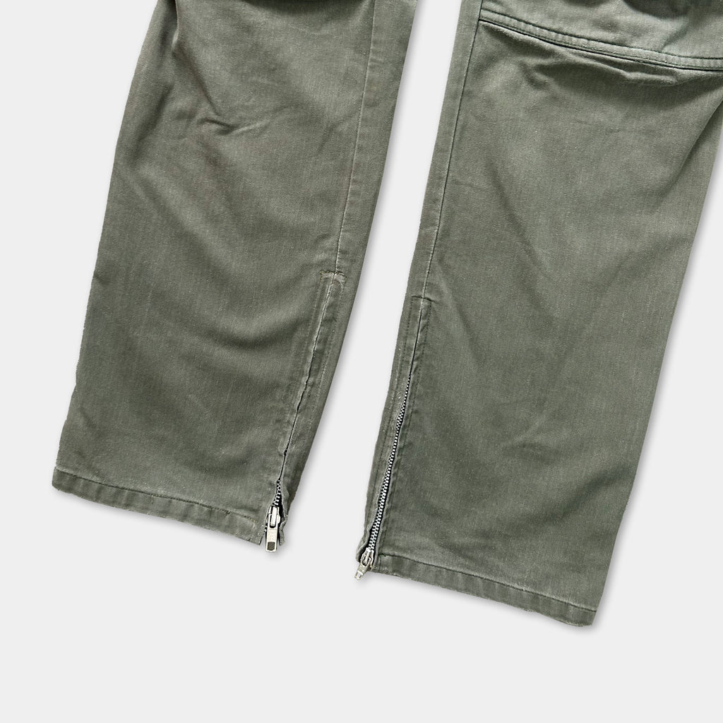 a pair of olive green cargo pants with zippers on the sides.