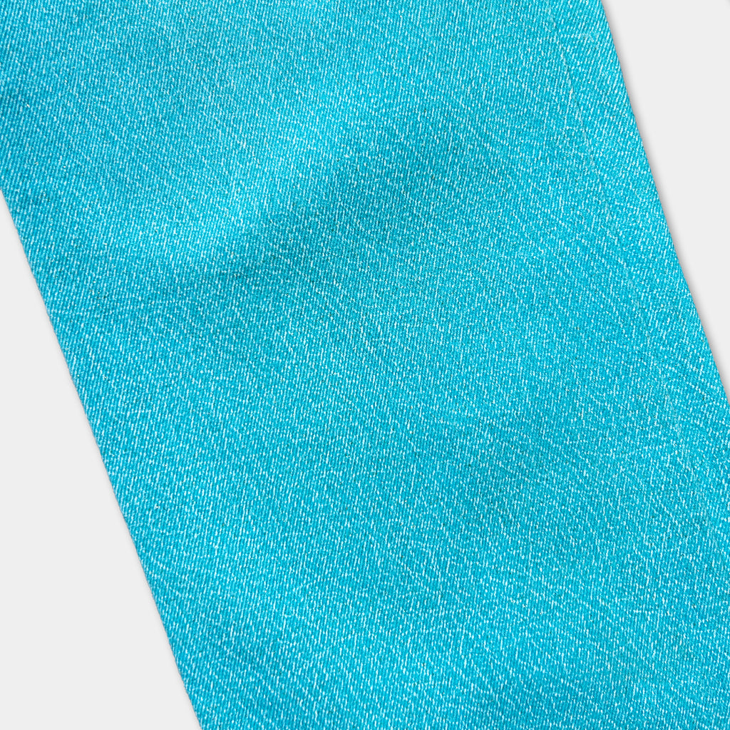 A close-up view of a bright turquoise fabric, with a textured and wrinkled appearance.
