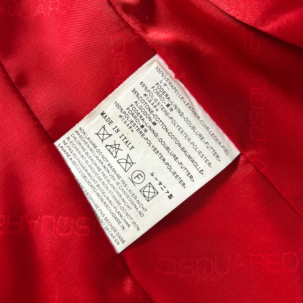 a close-up view of a red fabric with a white label attached to it, which contains text and symbols.