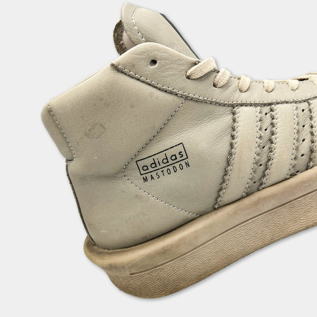 A close-up of a tan Adidas sneaker with the brand name "adidas" and the model name "Mastodon" printed on it.