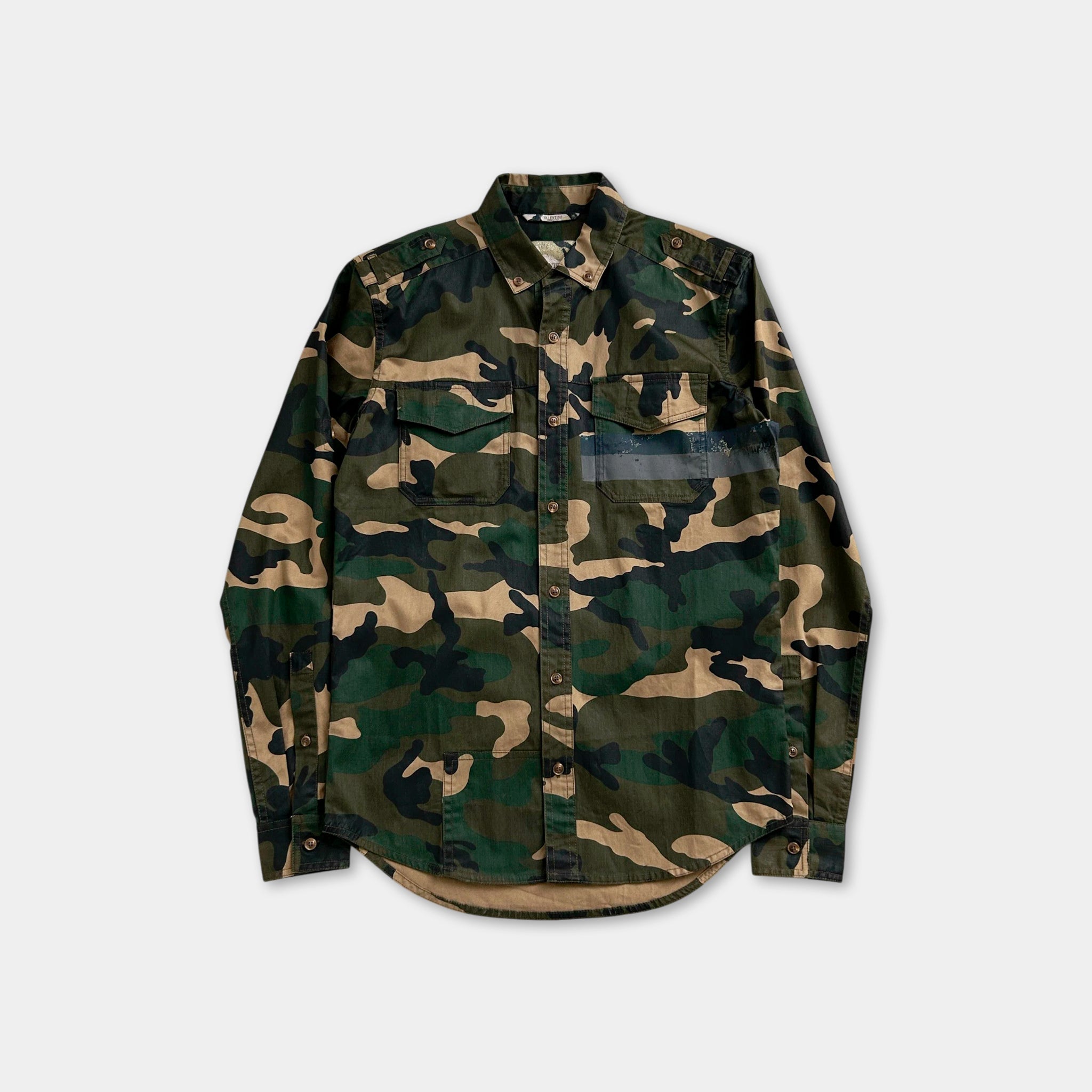 A camouflage-patterned long-sleeved shirt is displayed against a white background.