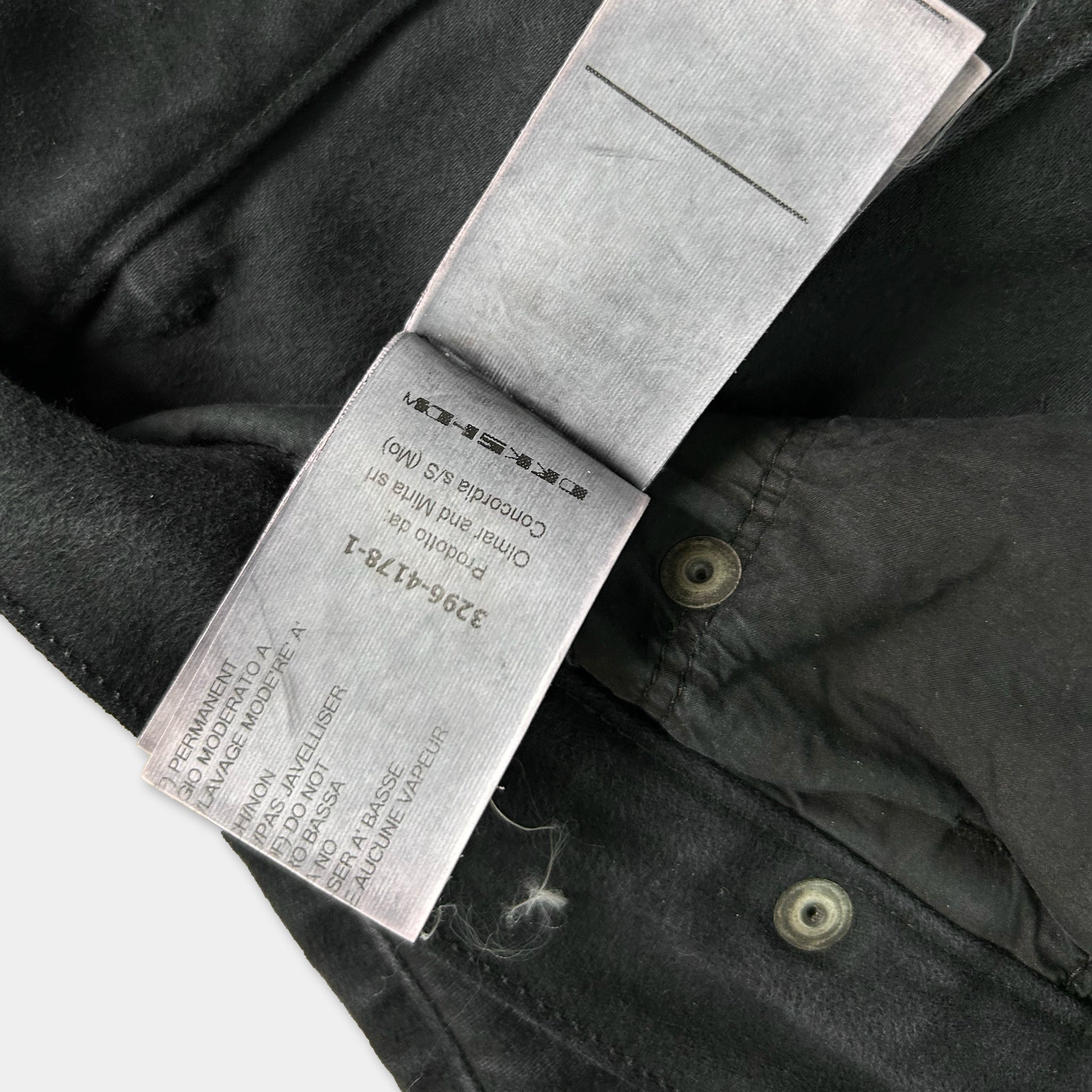 a close-up view of a black fabric, possibly a piece of clothing, with a label attached to it. The label appears to contain text and instructions related to the garment, but the exact wording is not clearly visible due to the angle and focus of the photograph.
