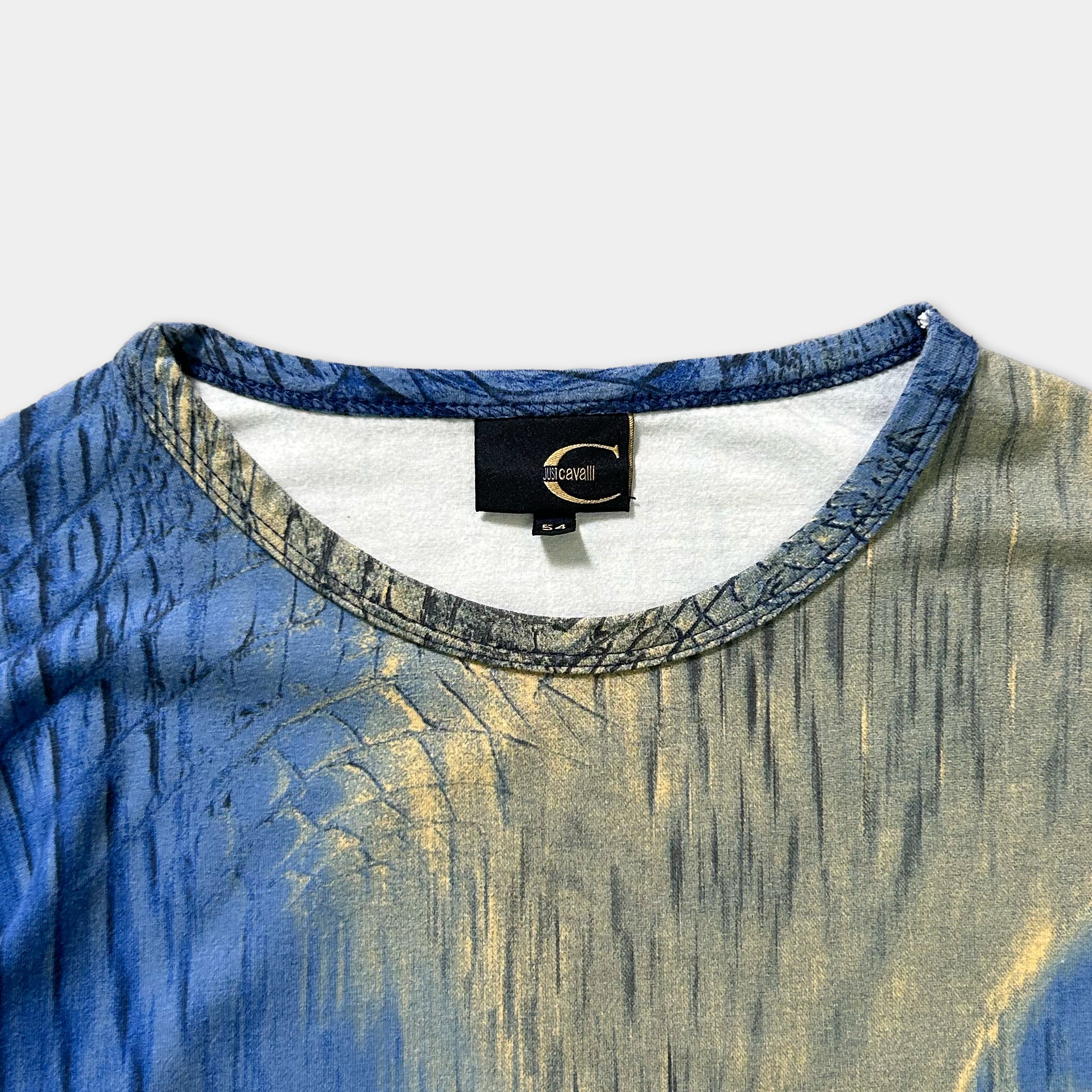 a close-up view of a blue and gold patterned shirt, with a label visible on the collar.