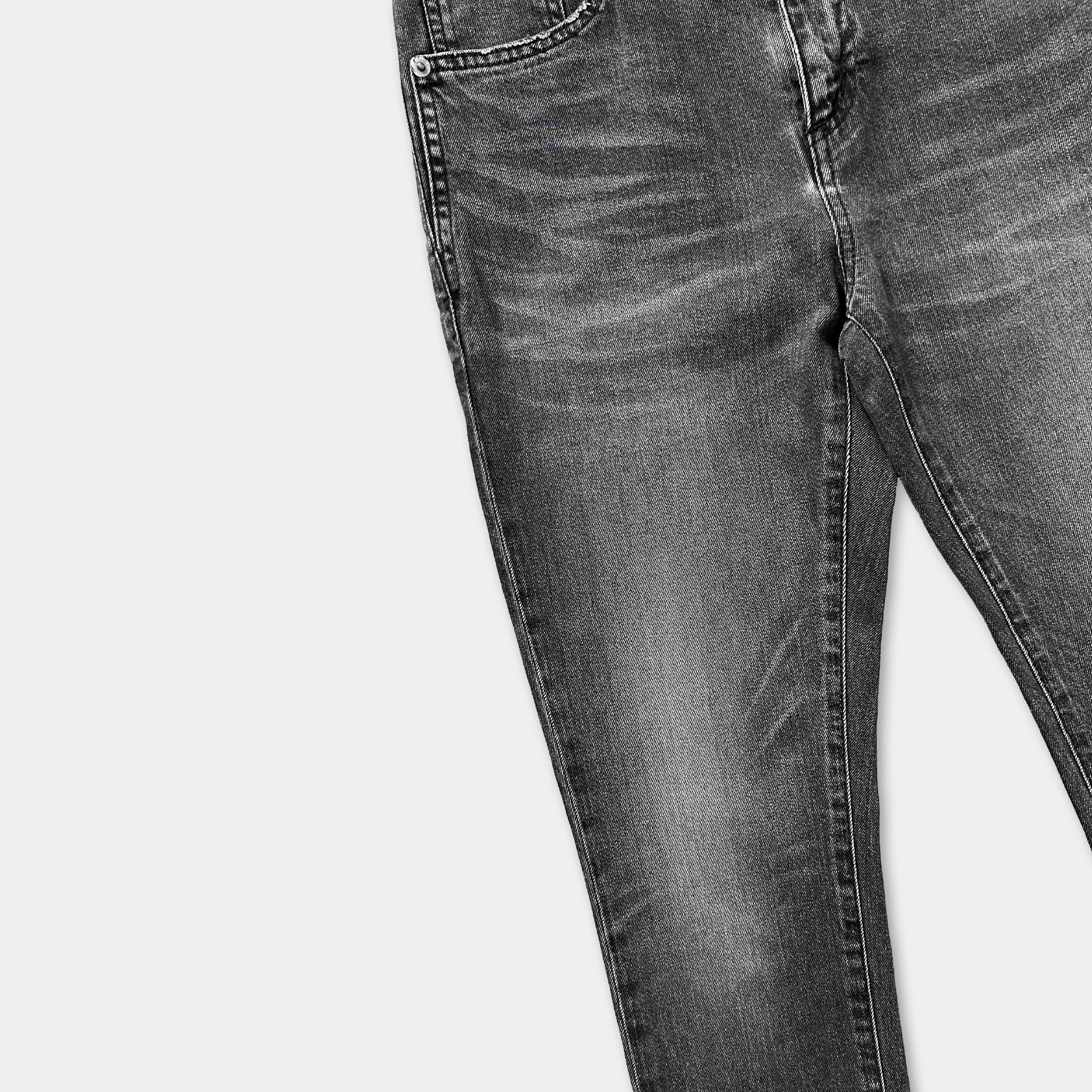 A pair of black jeans with visible signs of wear and tear, including faded and distressed fabric.