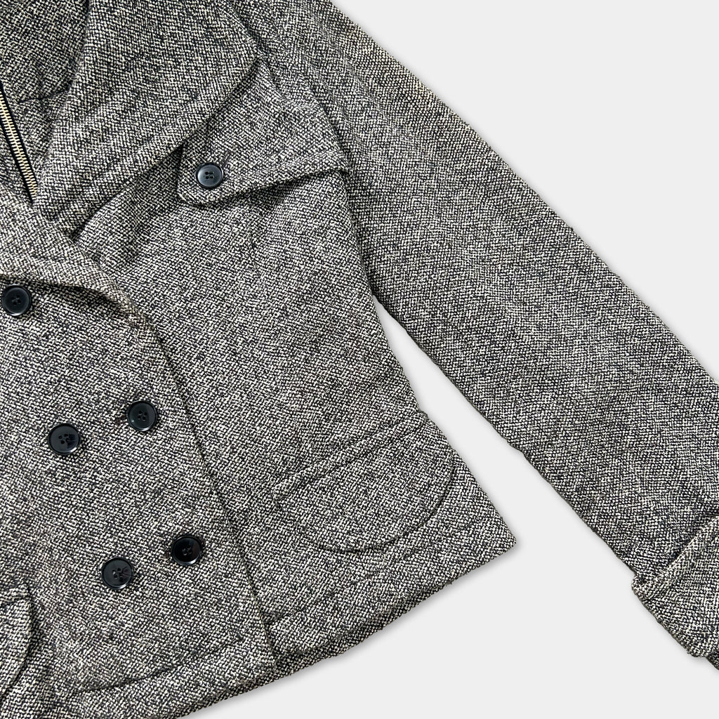 A close-up view of a gray tweed jacket with black buttons, showcasing the fabric and design details.
