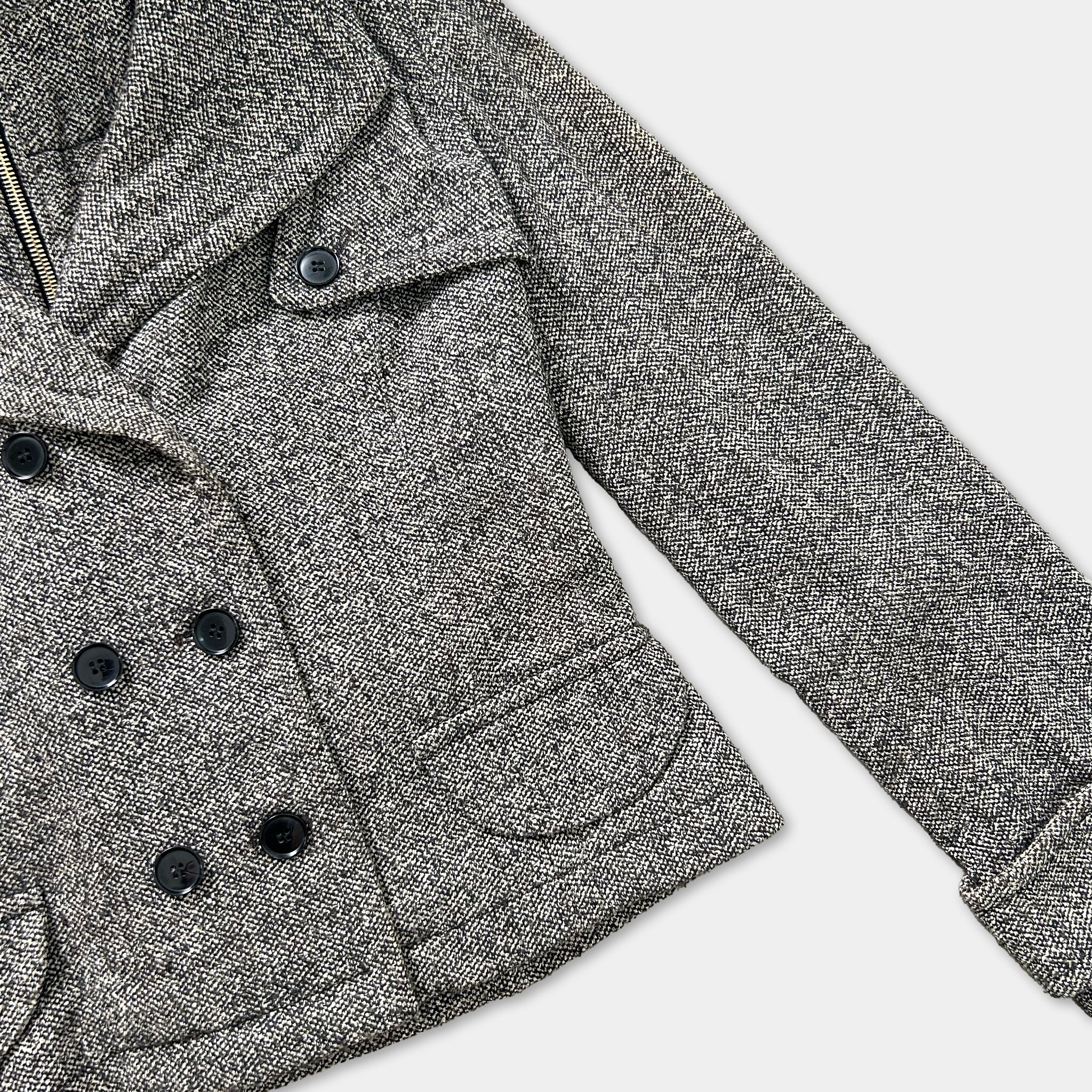 A close-up view of a gray tweed jacket with black buttons, showcasing the fabric and design details.