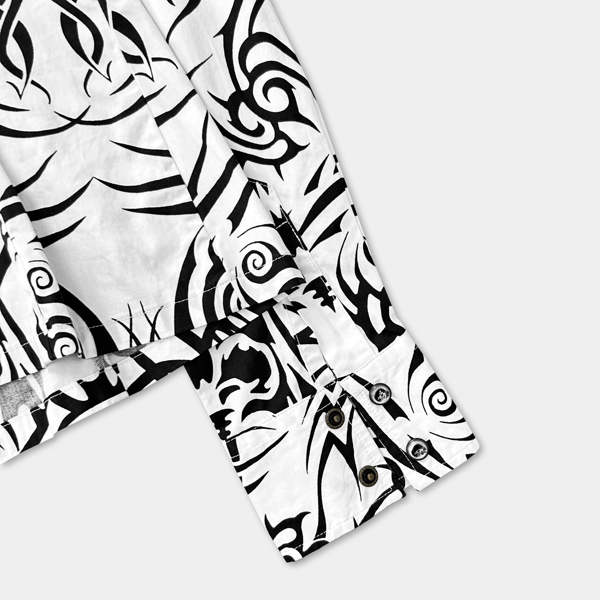 a close-up view of a white shirt with a black and white patterned design, including swirls and other abstract shapes.