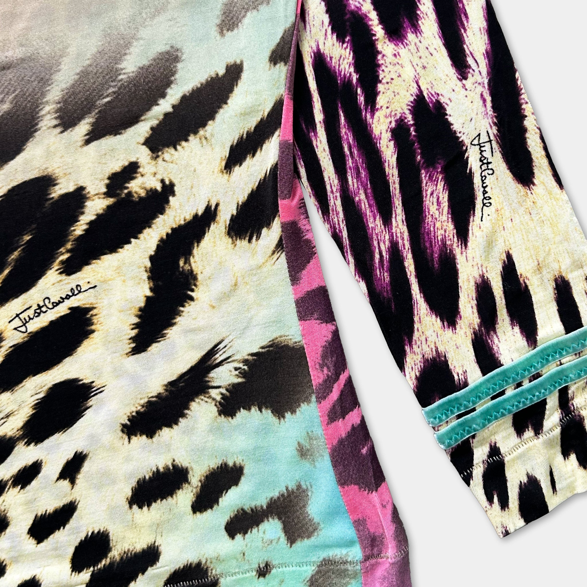 a long-sleeved shirt with a striking leopard print pattern in shades of pink, black, and white. The shirt has a teal accent on the sleeves, adding a pop of color to the overall design.