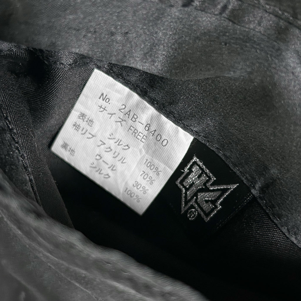 a close-up view of a black fabric, possibly a piece of clothing, with a label attached to it. The label appears to contain text in a foreign language, and there is a logo or symbol on the label.