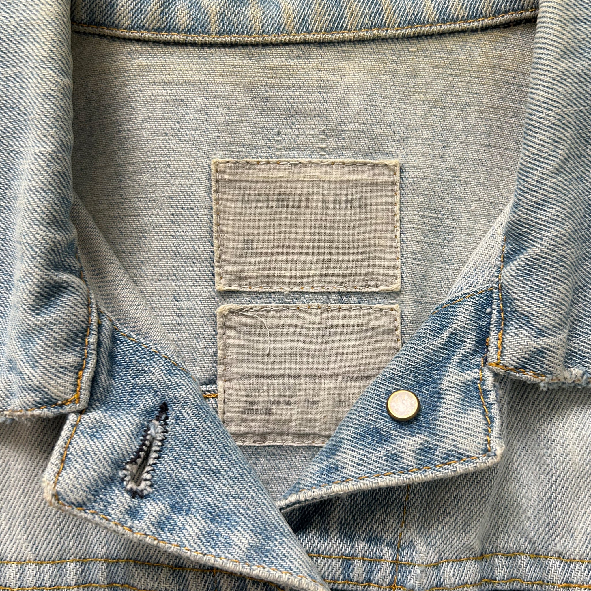 a close-up view of a denim jacket, focusing on the collar and the label.