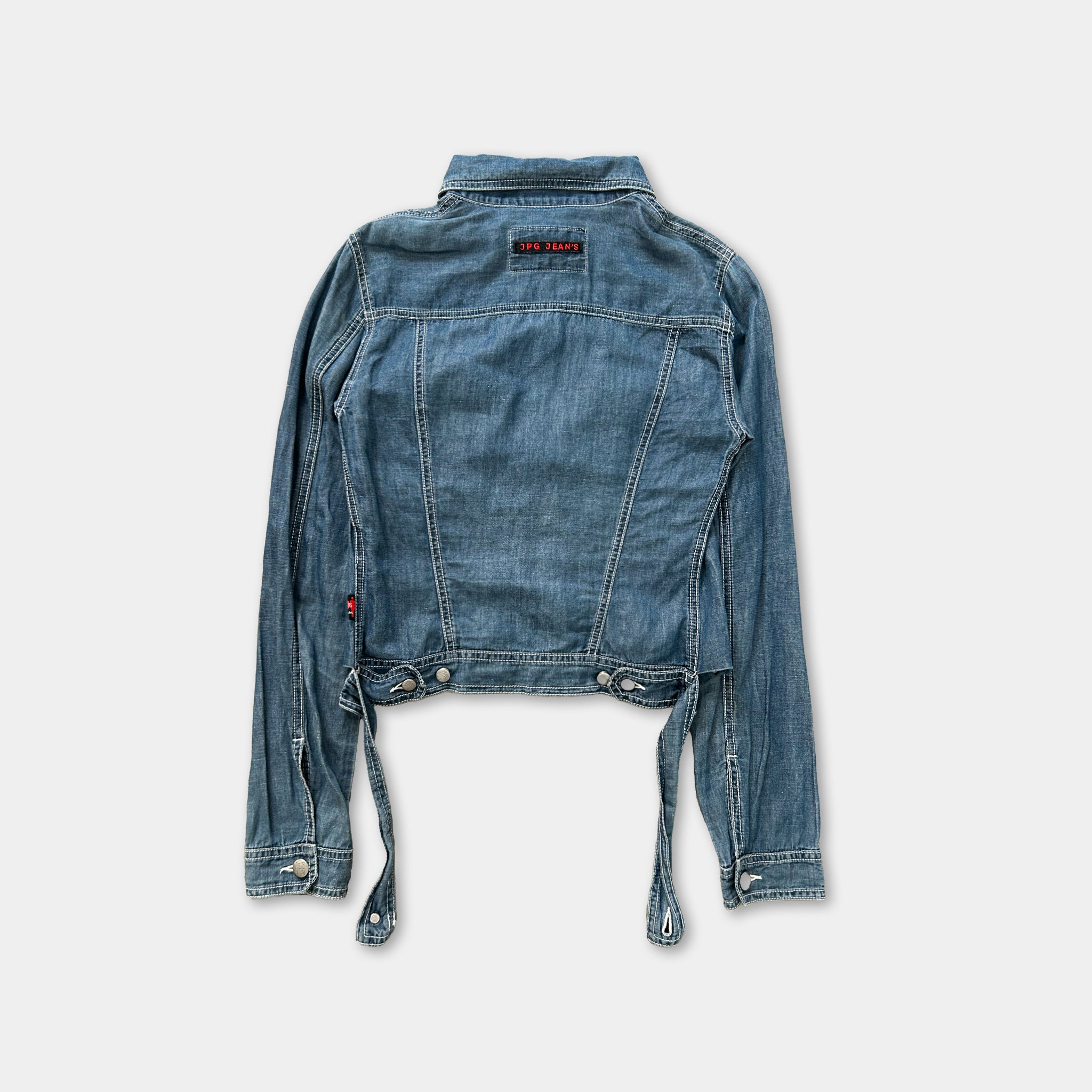 A denim jacket with a red tag on the back, hanging against a white background.
