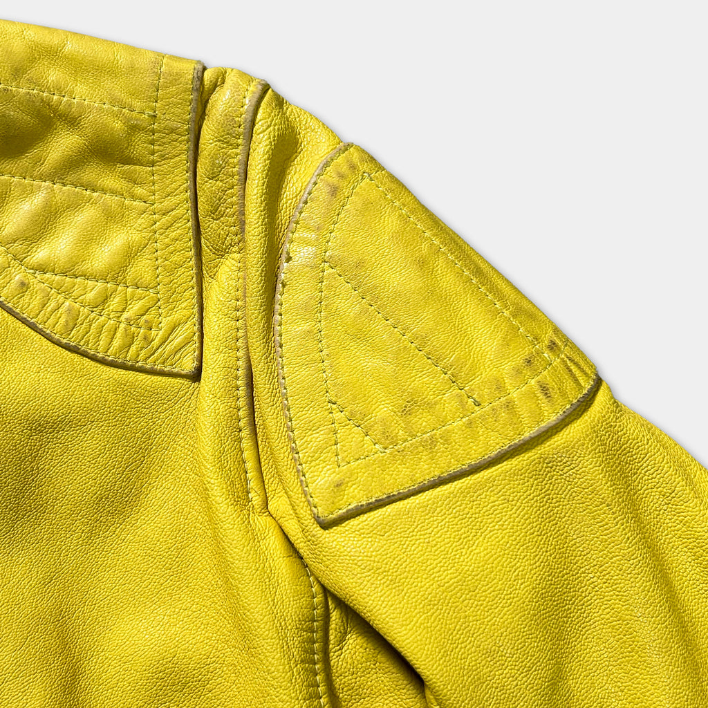 A close-up view of a yellow leather jacket, focusing on the shoulder area.