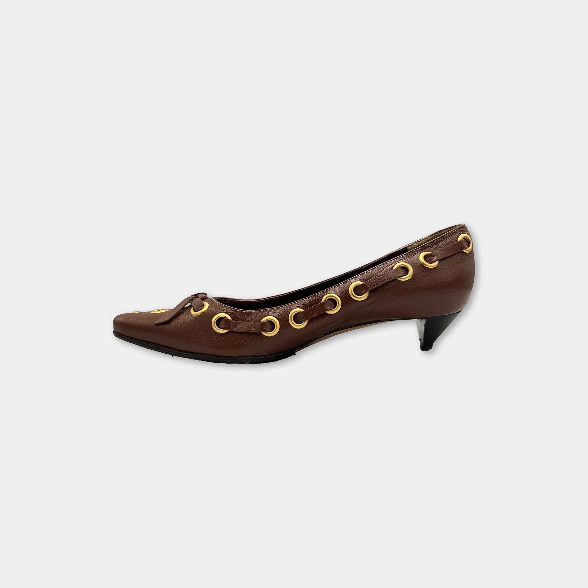 A brown leather shoe with gold-colored buckles and straps.