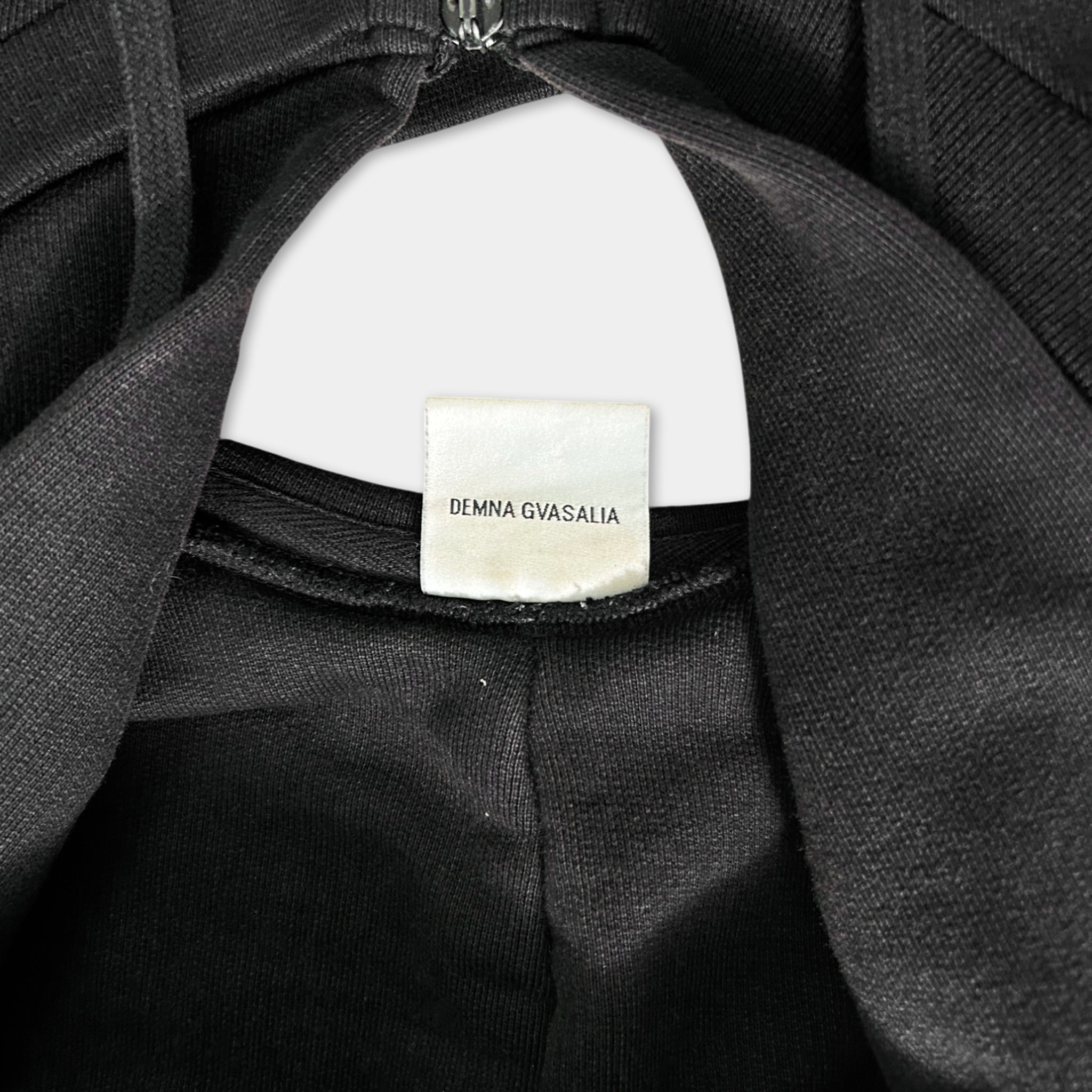 a close-up view of a black garment, possibly a jacket or sweater, with a label attached to it.