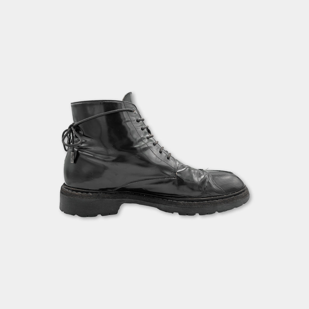 A single black, shiny boot with a lace-up design.