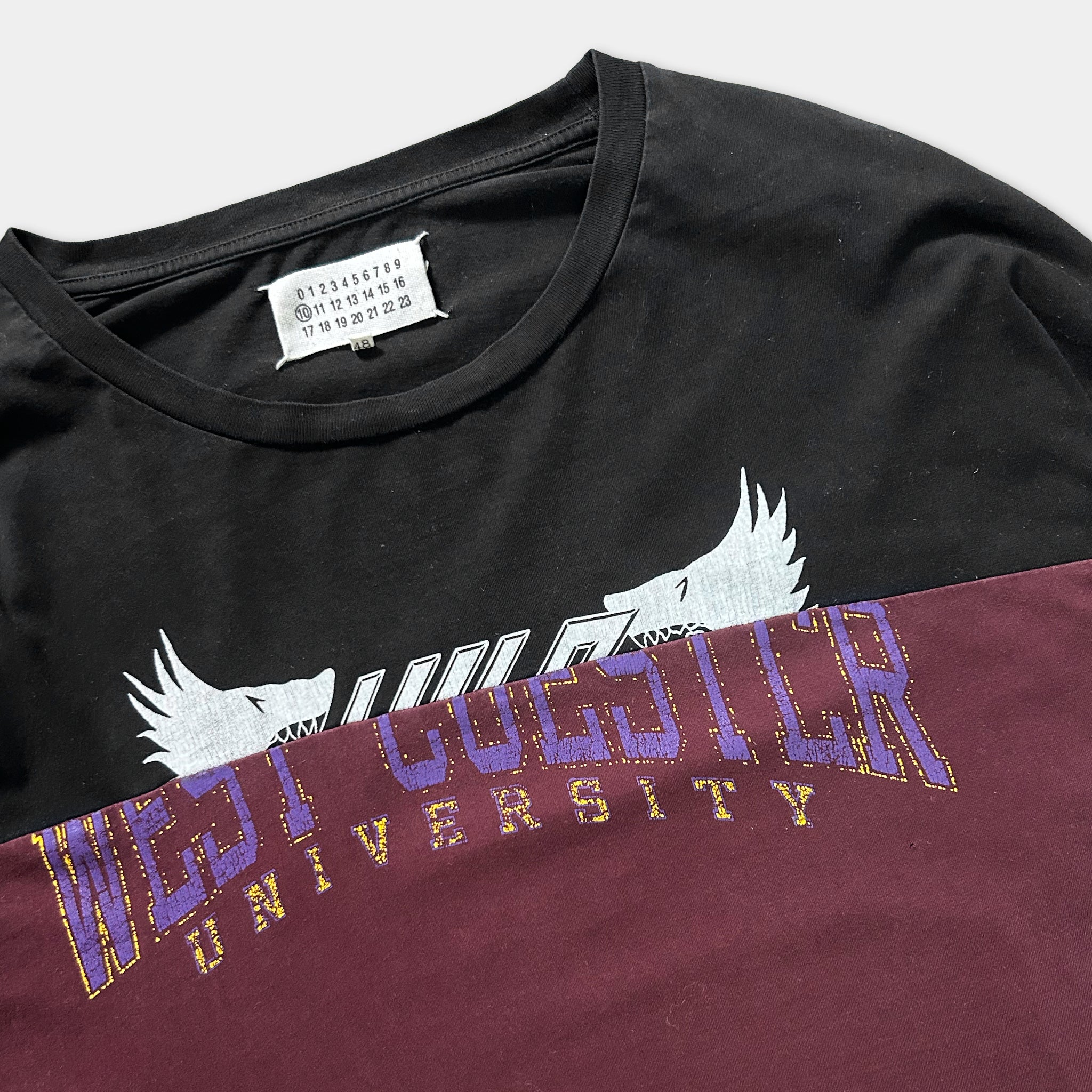A black t-shirt with a white and purple graphic design, featuring the text "WEST UNIVERSITY" printed on it.