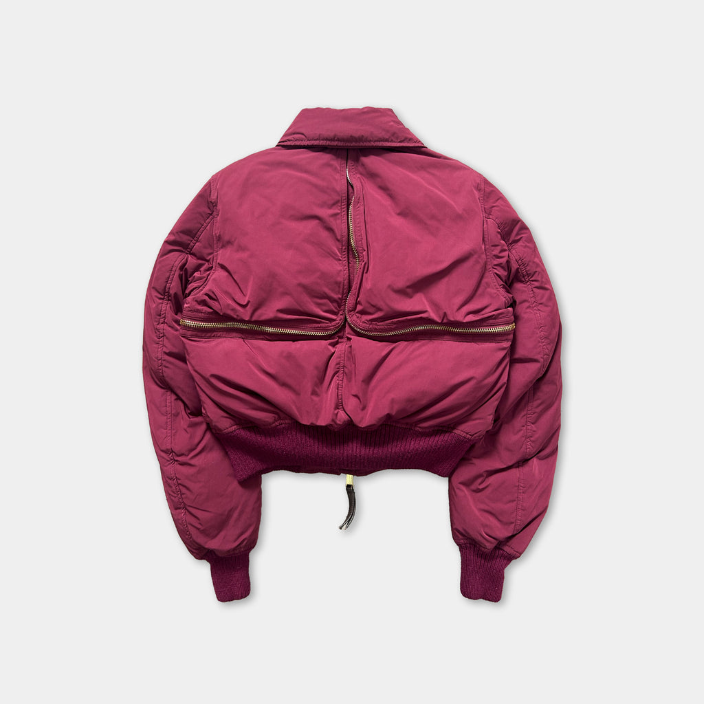 A maroon-colored jacket with a zipper running down the back, displayed against a white background.