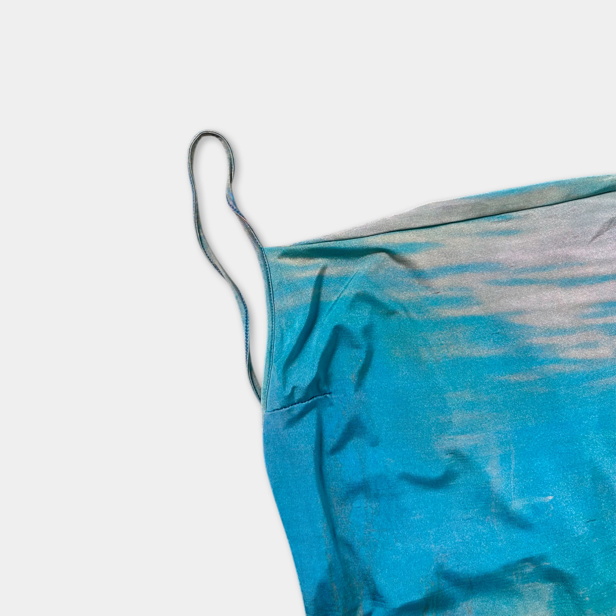 a piece of blue fabric with a handle or loop on the edge, resting on a plain white background.