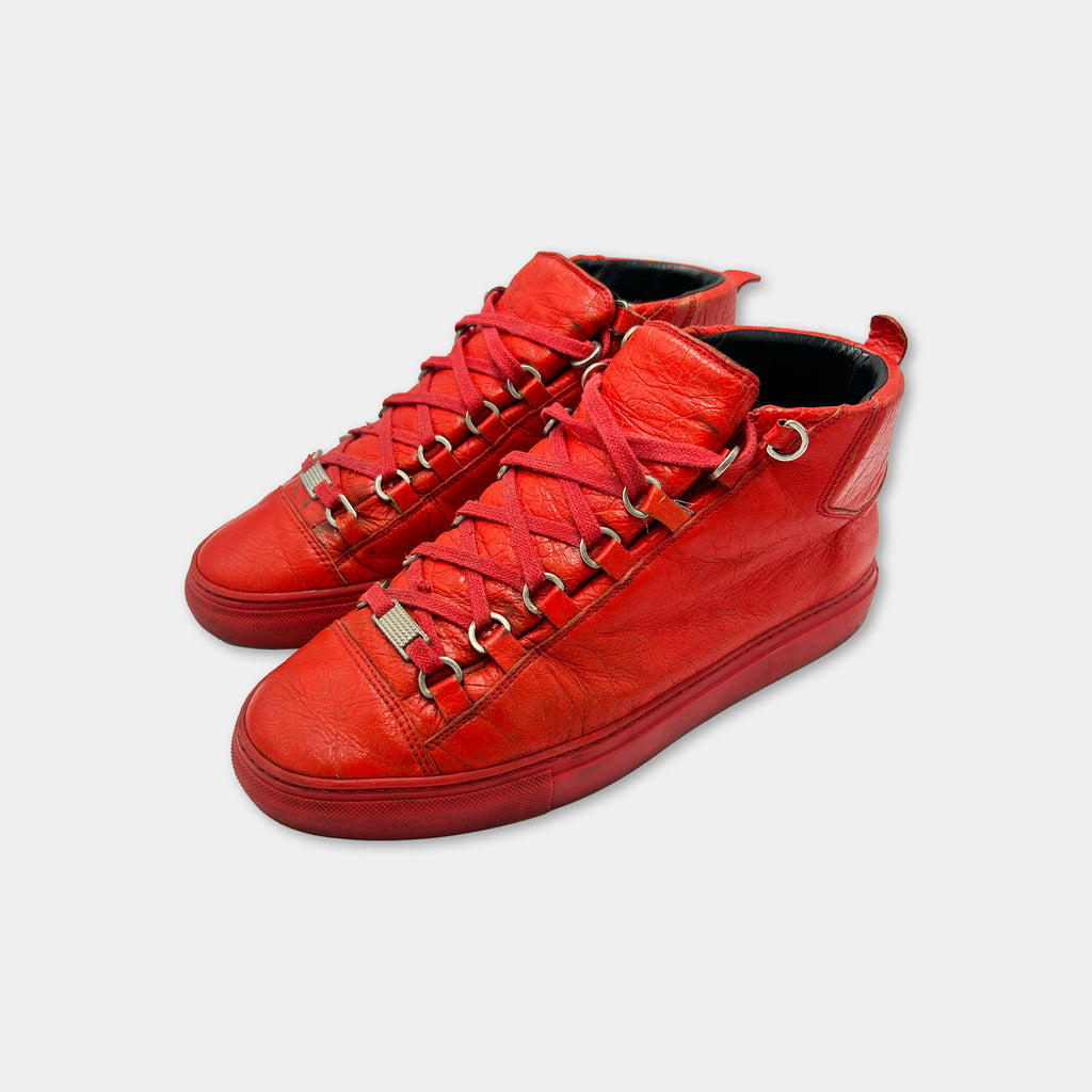 A pair of bright red high-top sneakers with metal studs on the sides.