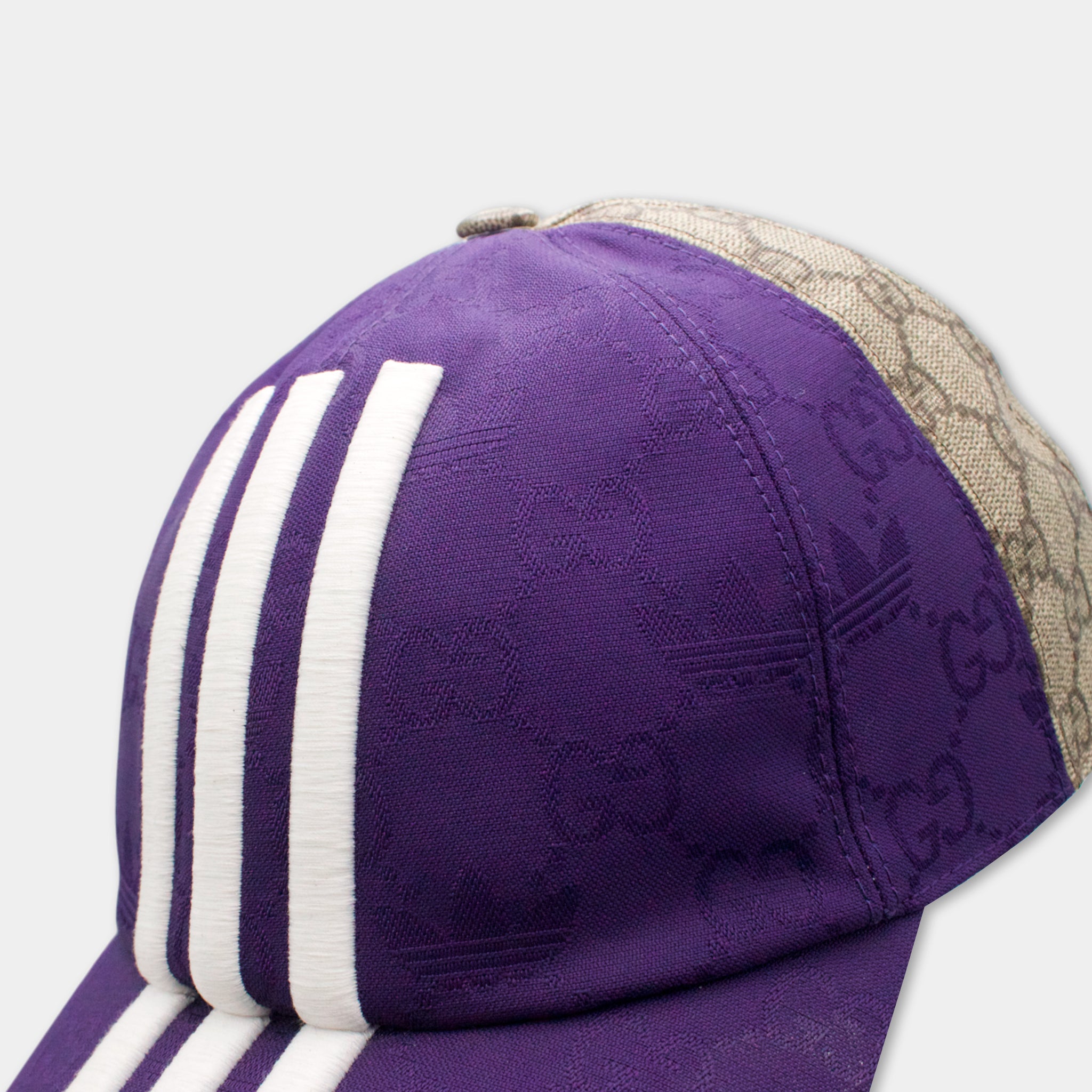 A close-up view of a purple baseball cap with white stripes and a beige patterned brim.