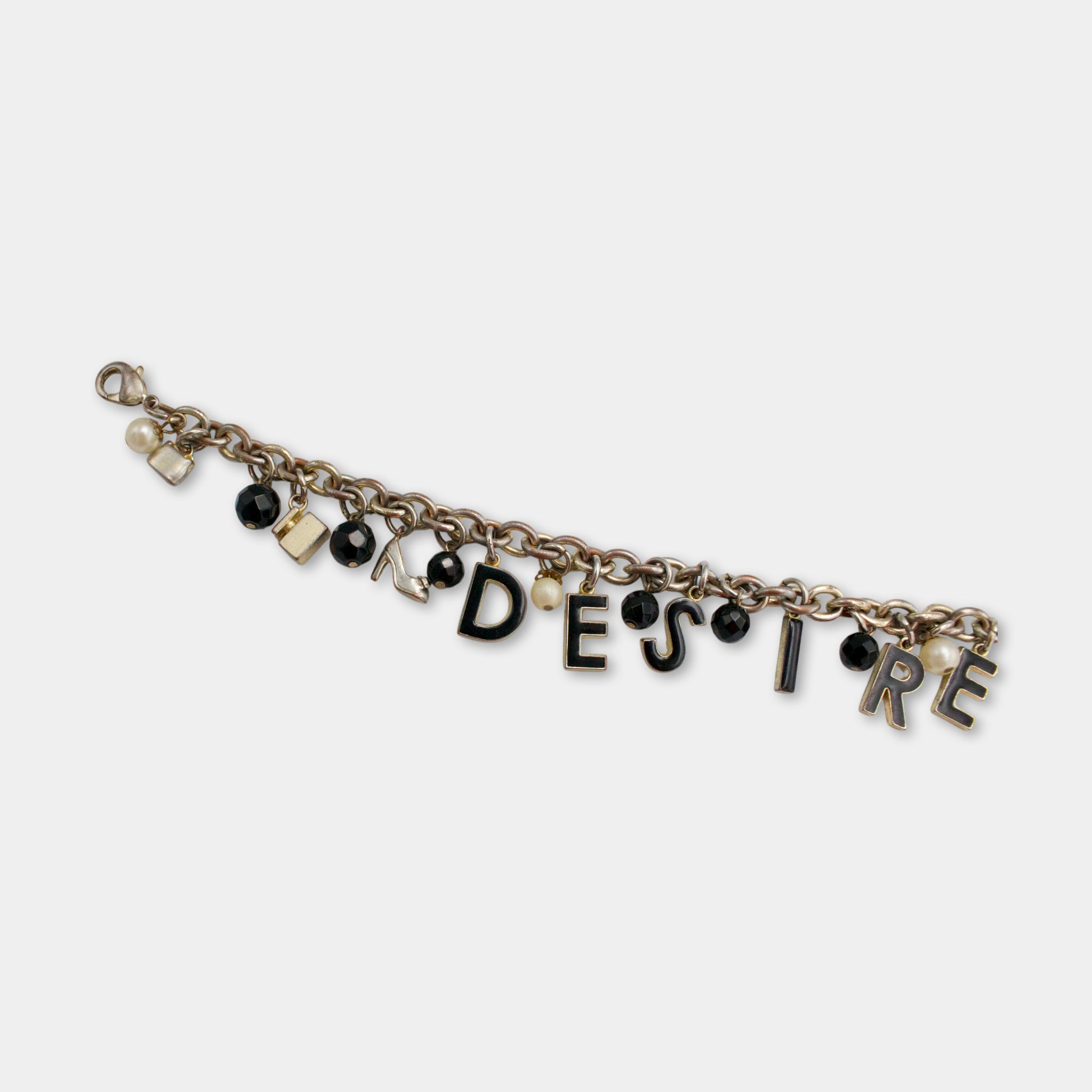 A bracelet with the word "DESIRE" spelled out in black letters, along with various charms and beads attached to it.