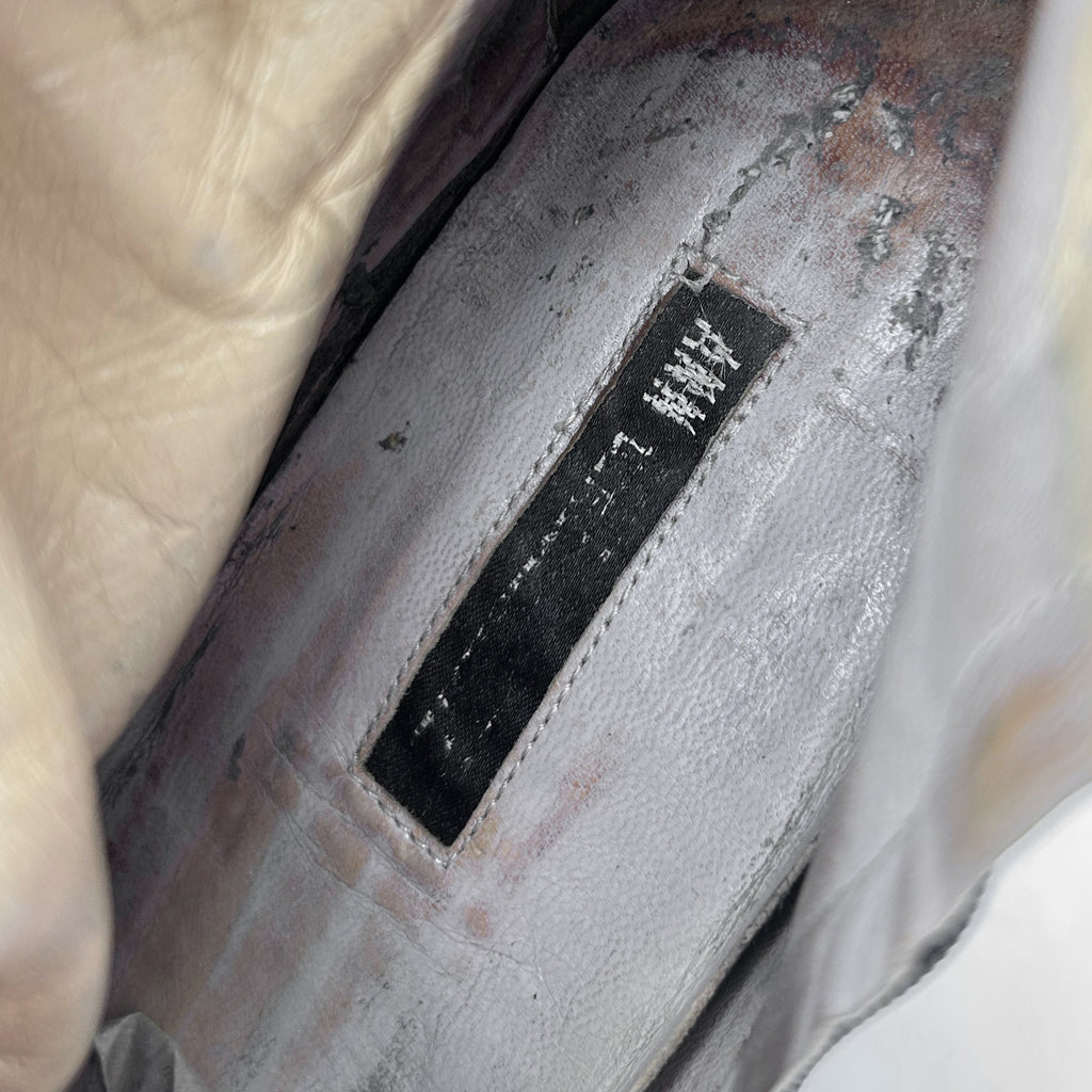 a close-up view of a worn and dirty shoe, with a black label or tag attached to it.