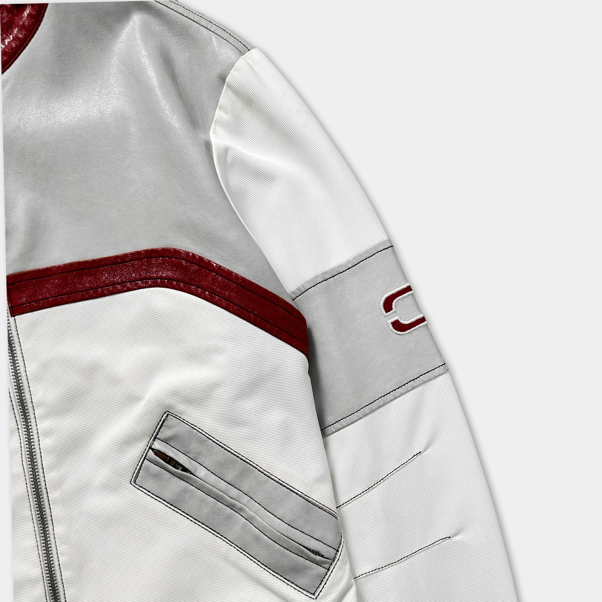 A close-up view of a white and red jacket with a red stripe and a gray stripe on the sleeve.